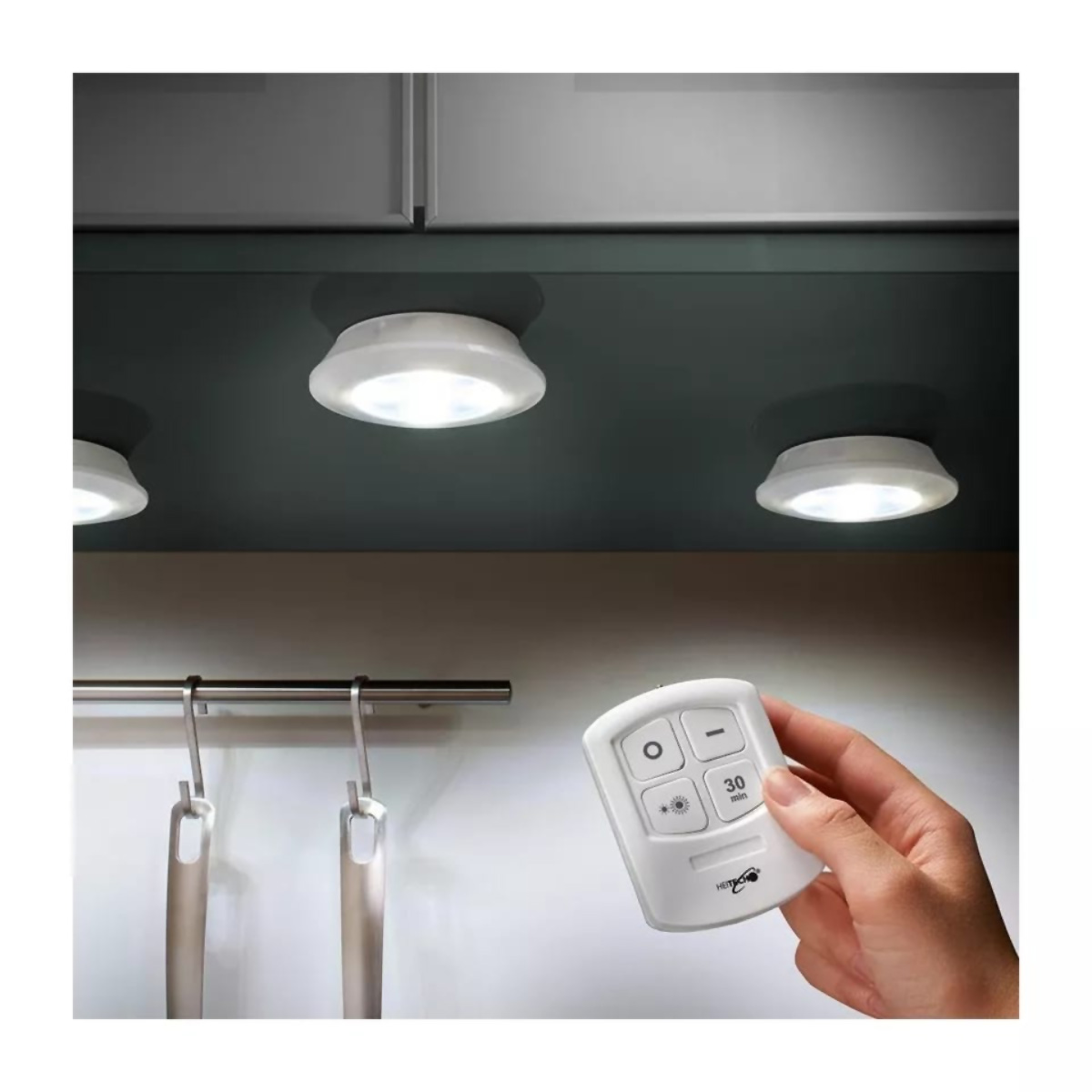 Tres luces LED blancas bajo un armario, controladas por un mando a distancia.