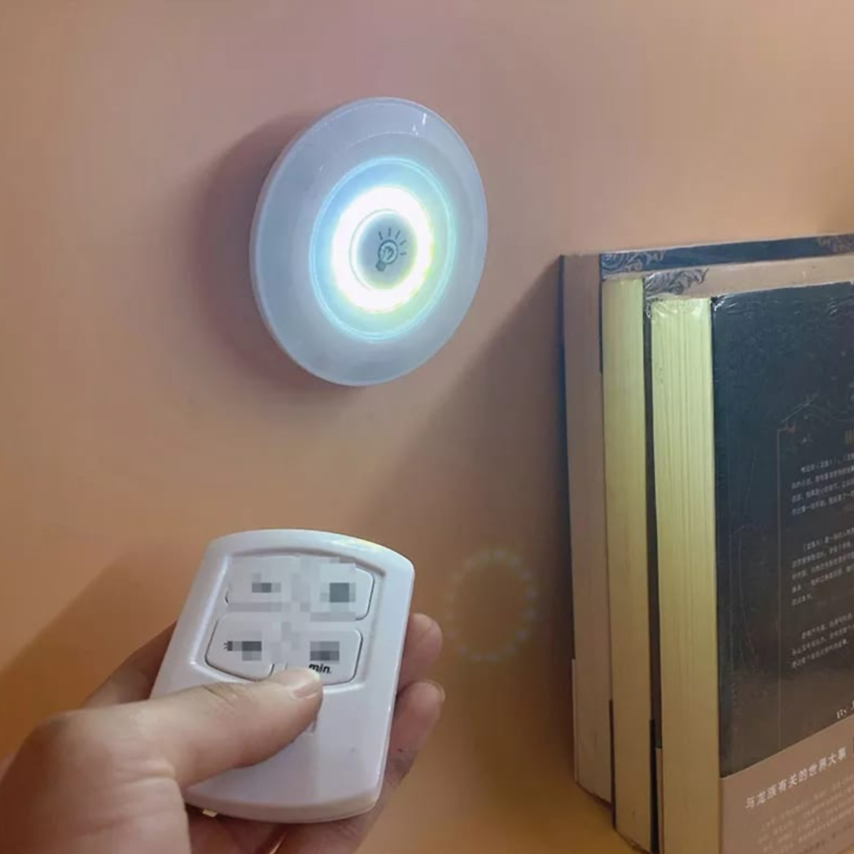 Luz de pared blanca con control remoto. Luz en pared rosa, junto a libros.
