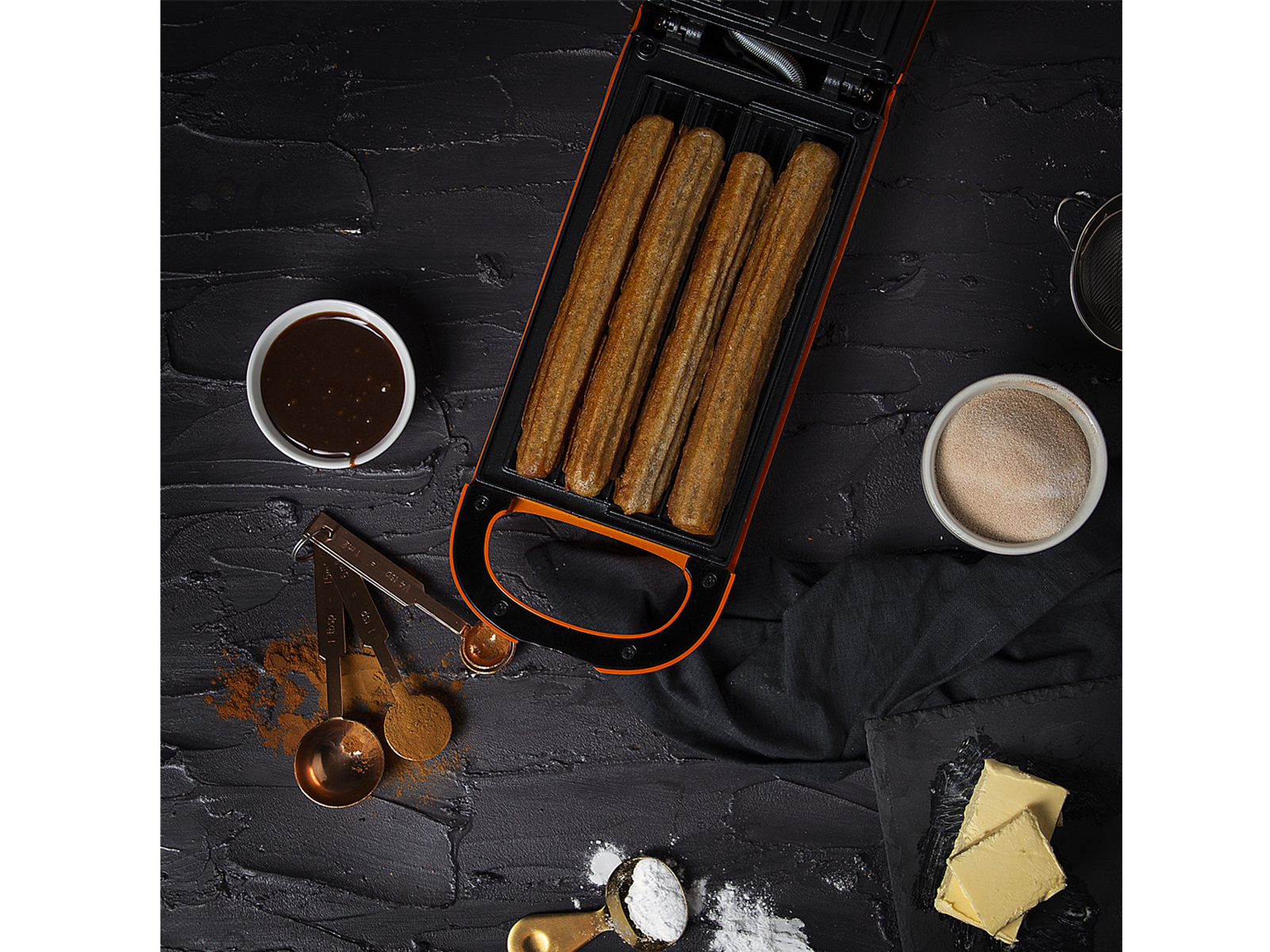Vista dall'alto di una macchina per churros con churros, cioccolato, cannella e altri ingredienti.