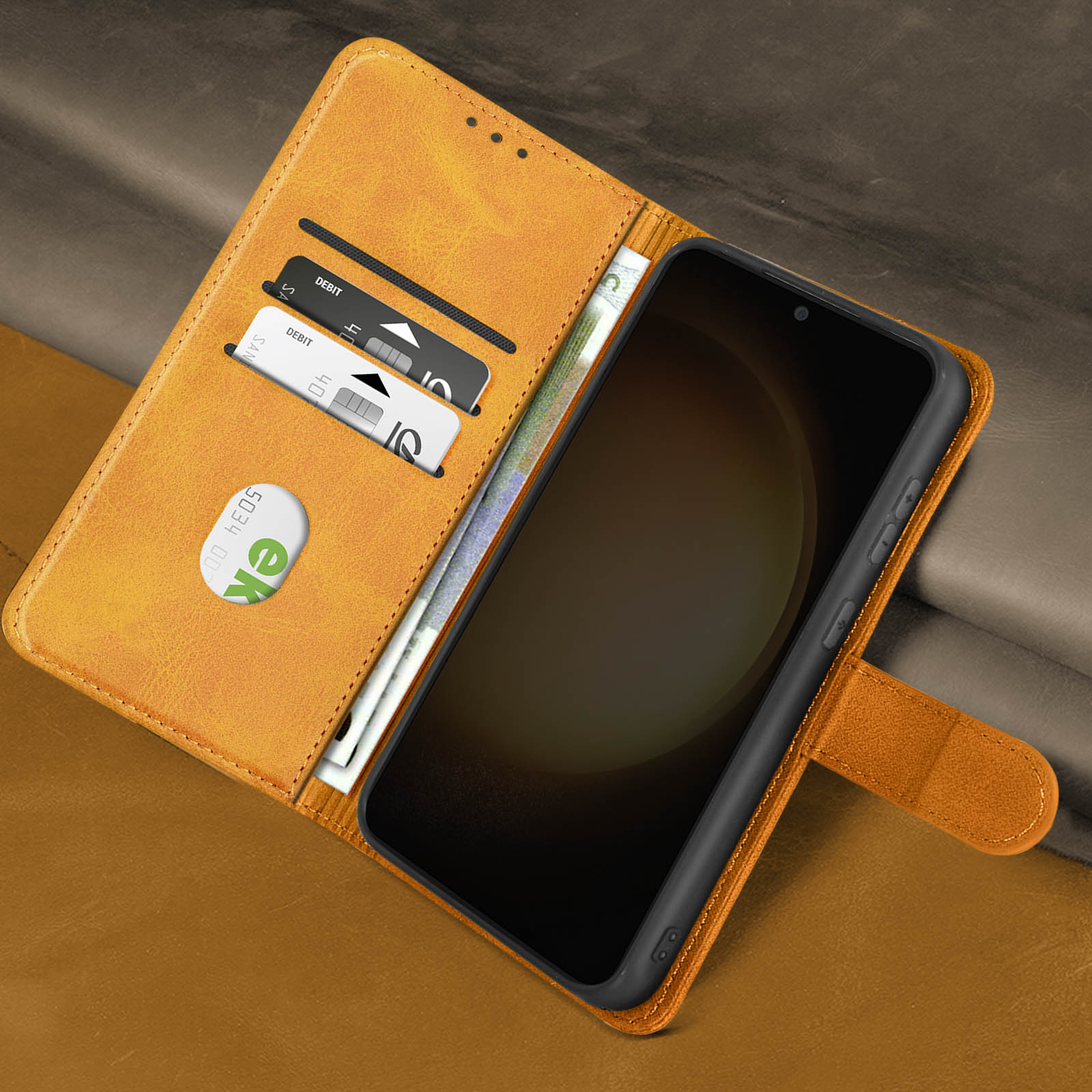 Custodia per telefono aperta con telefono dentro, carte di debito e denaro visibili su pelle.