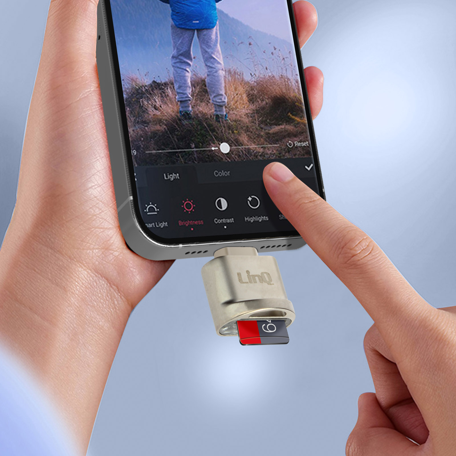 Una mano tiene uno smartphone con lettore di schede SD. Un dito tocca lo schermo.