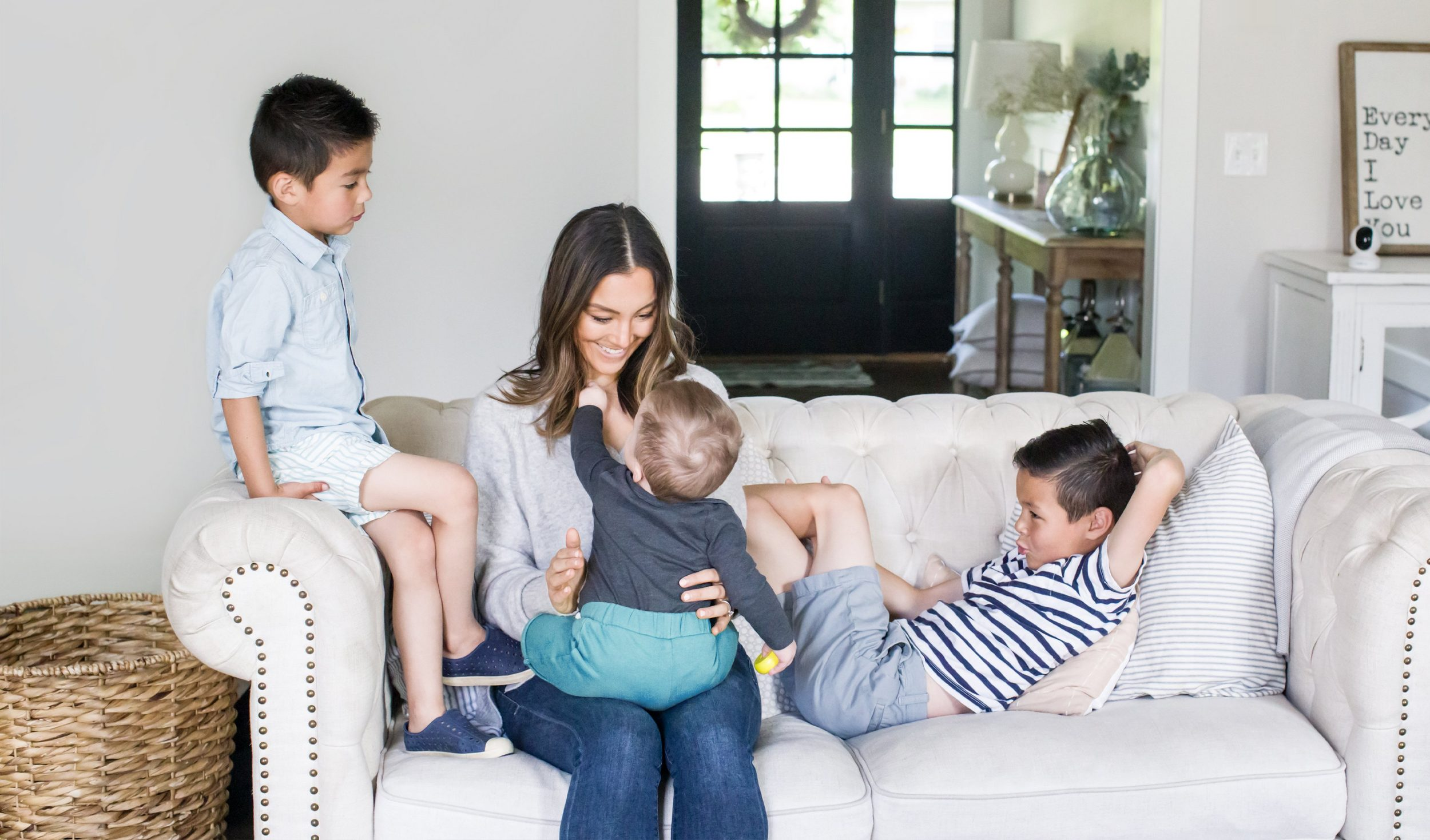 Eine vierköpfige Familie auf einem weißen Sofa in einem gut beleuchteten Wohnzimmer.