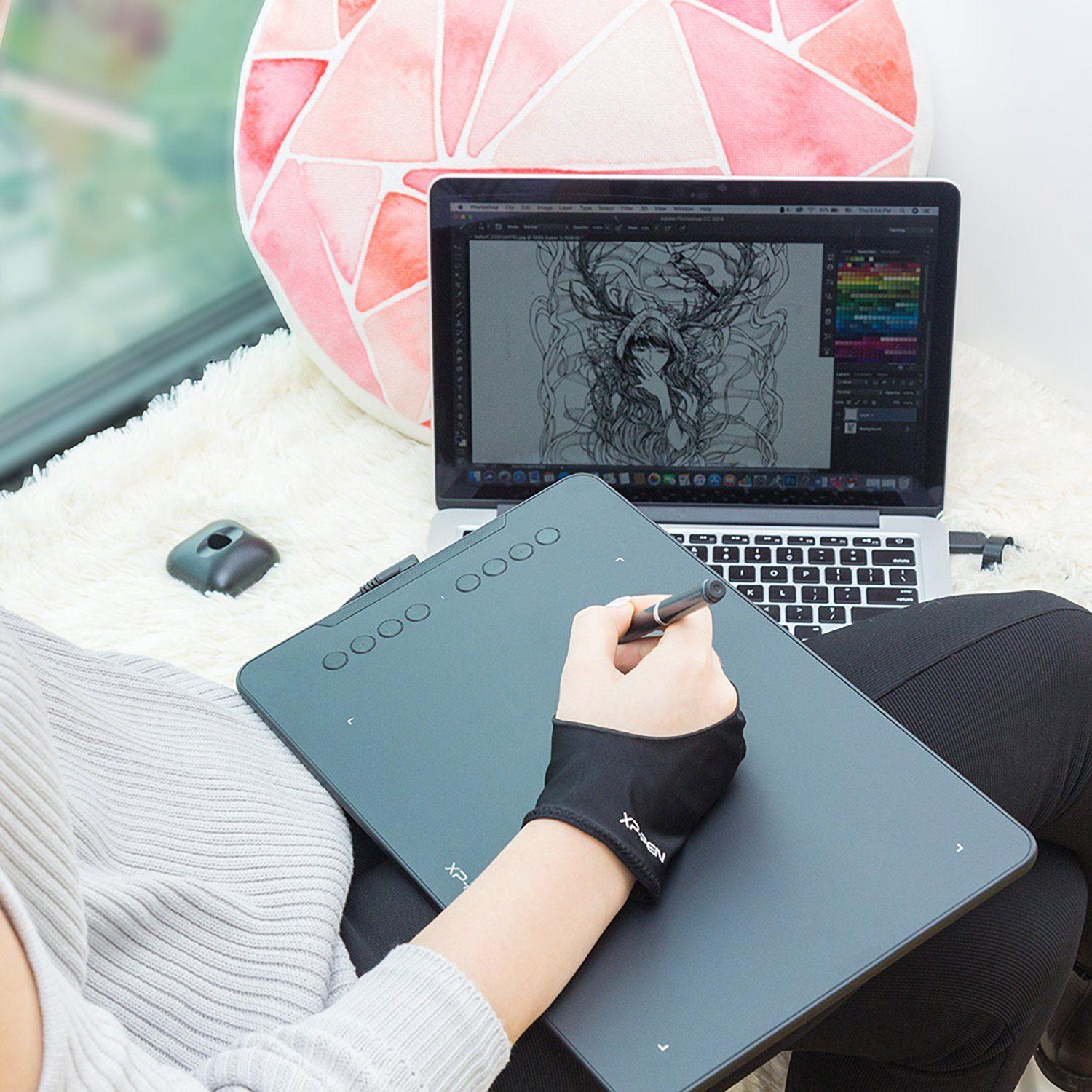 Una persona usa un tablet da disegno con una penna, seduta vicino a una finestra.