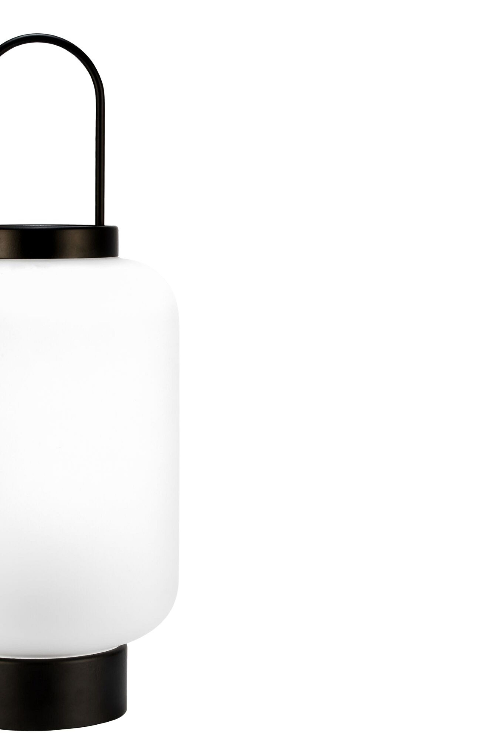 Biała latarnia z czarnym uchwytem i podstawą. Białe tło.