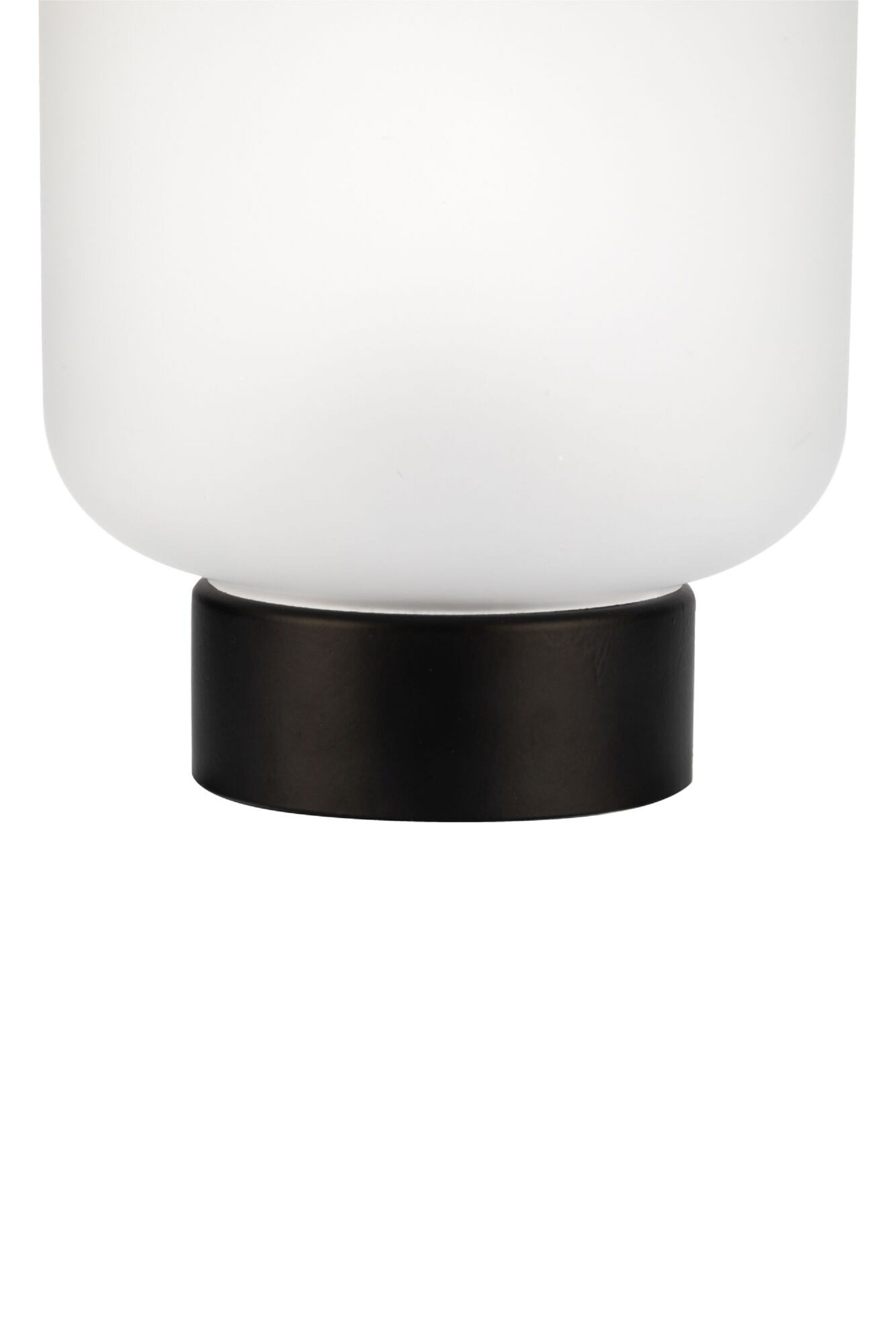 Zbliżenie białego, zaokrąglonego klosza lampy nad czarną, cylindryczną podstawą. Białe tło.
