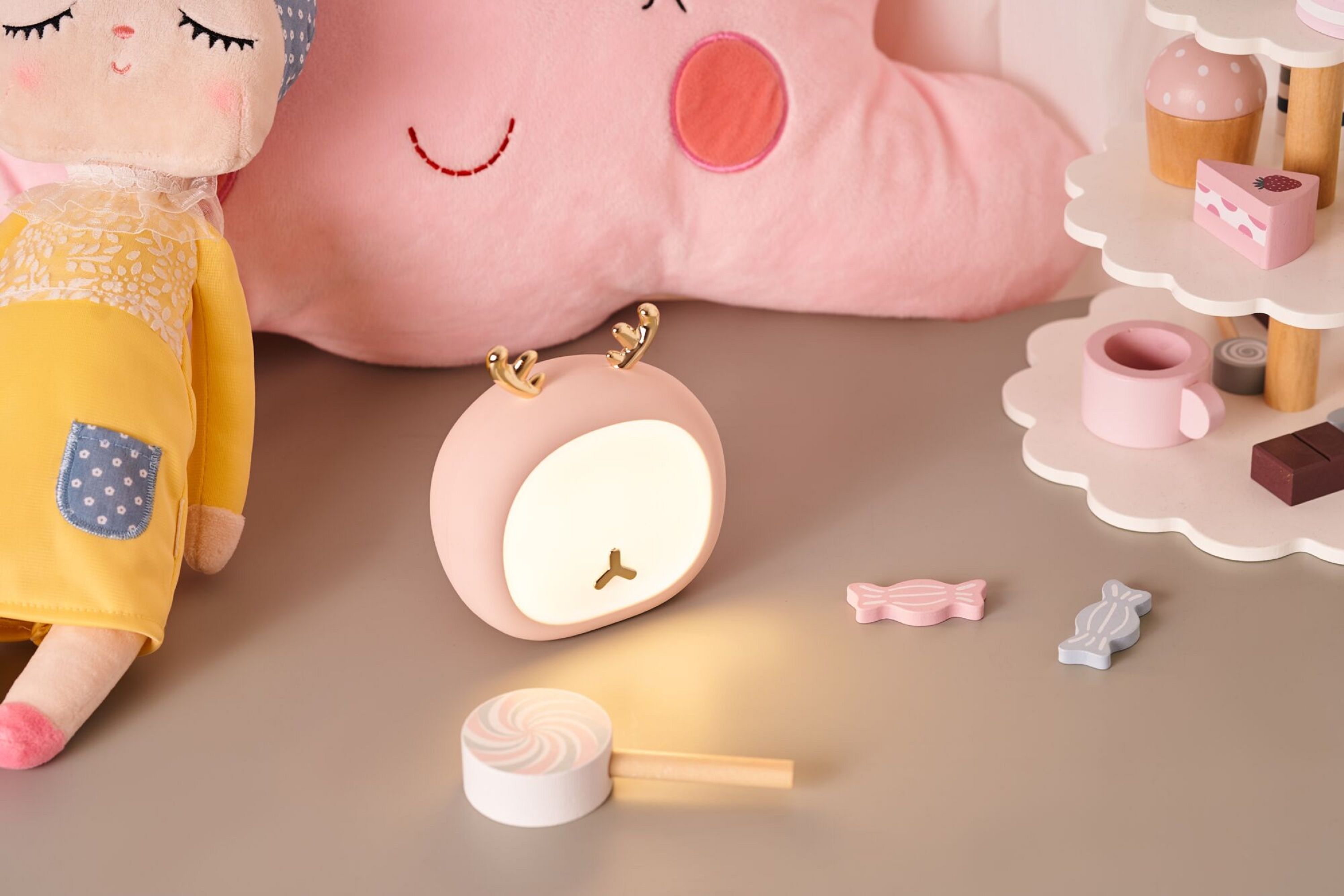 Ein rosa Hirsch-Nachtlicht, umgeben von Spielzeug wie einer Puppe und Süßigkeiten.