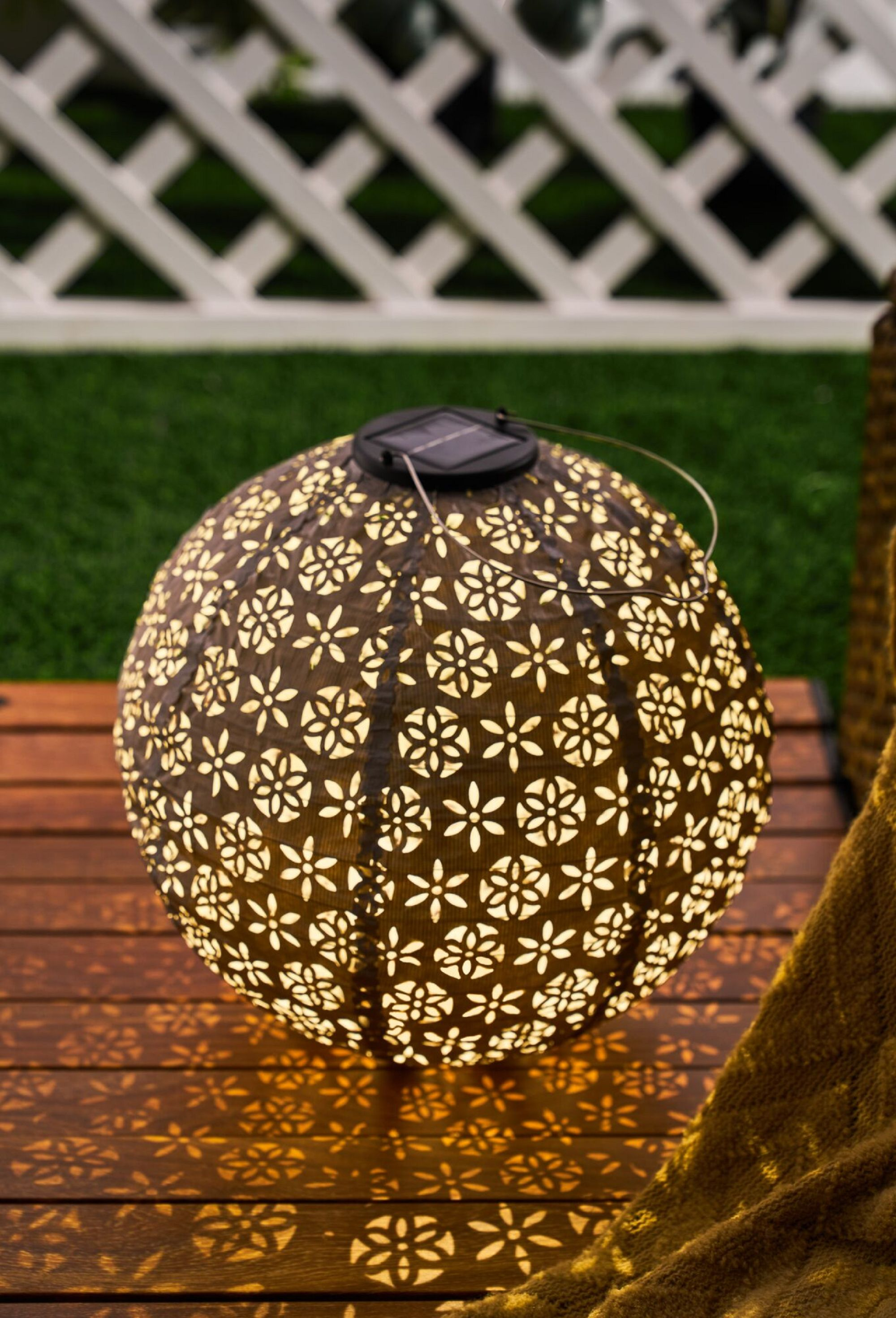 Brązowa, okrągła, zasilana energią słoneczną latarnia z wzorem rzucającym światło.