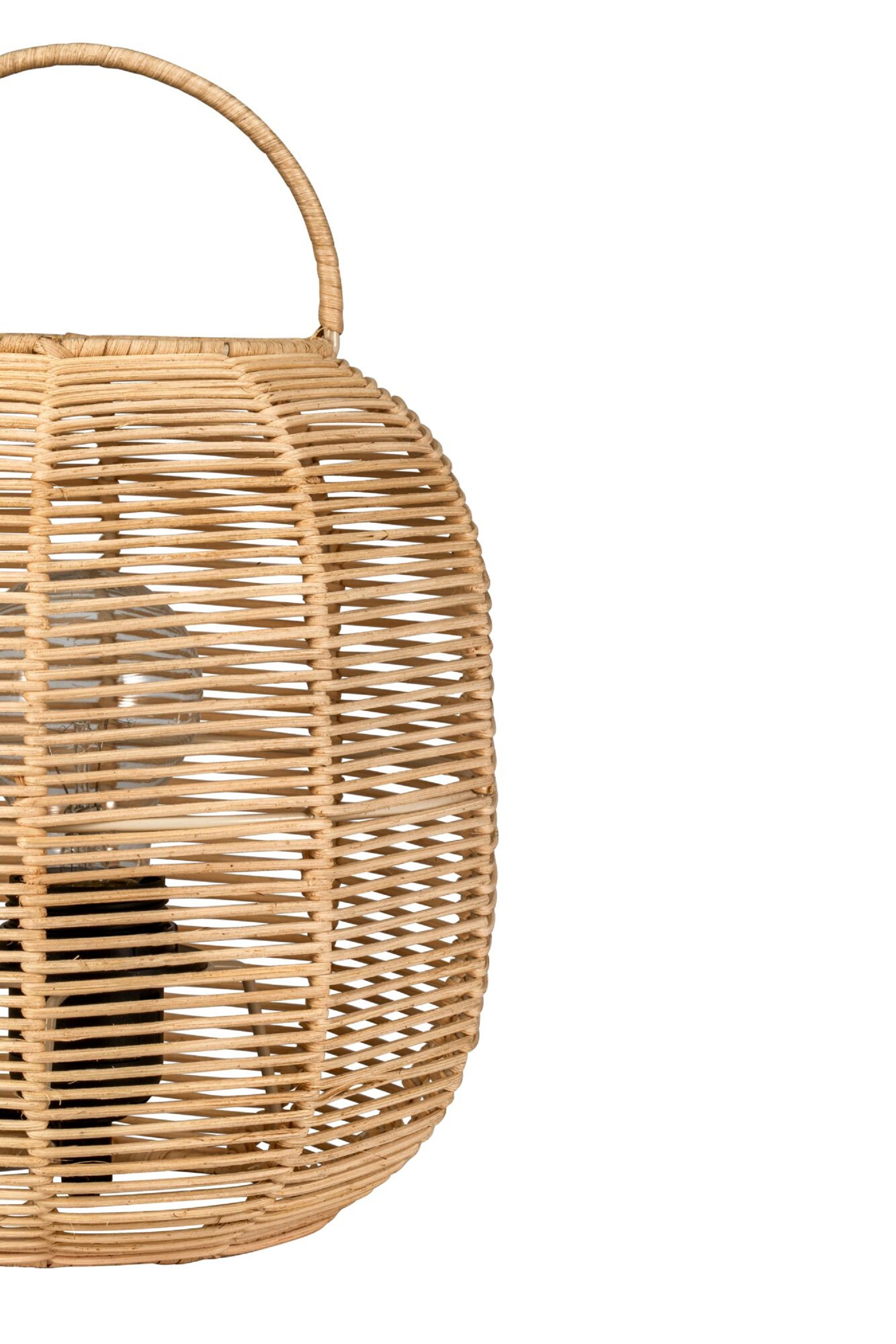 Wiklinowa latarnia z uchwytem, ​​stojąca na białej powierzchni. Światło świeci od wewnątrz.