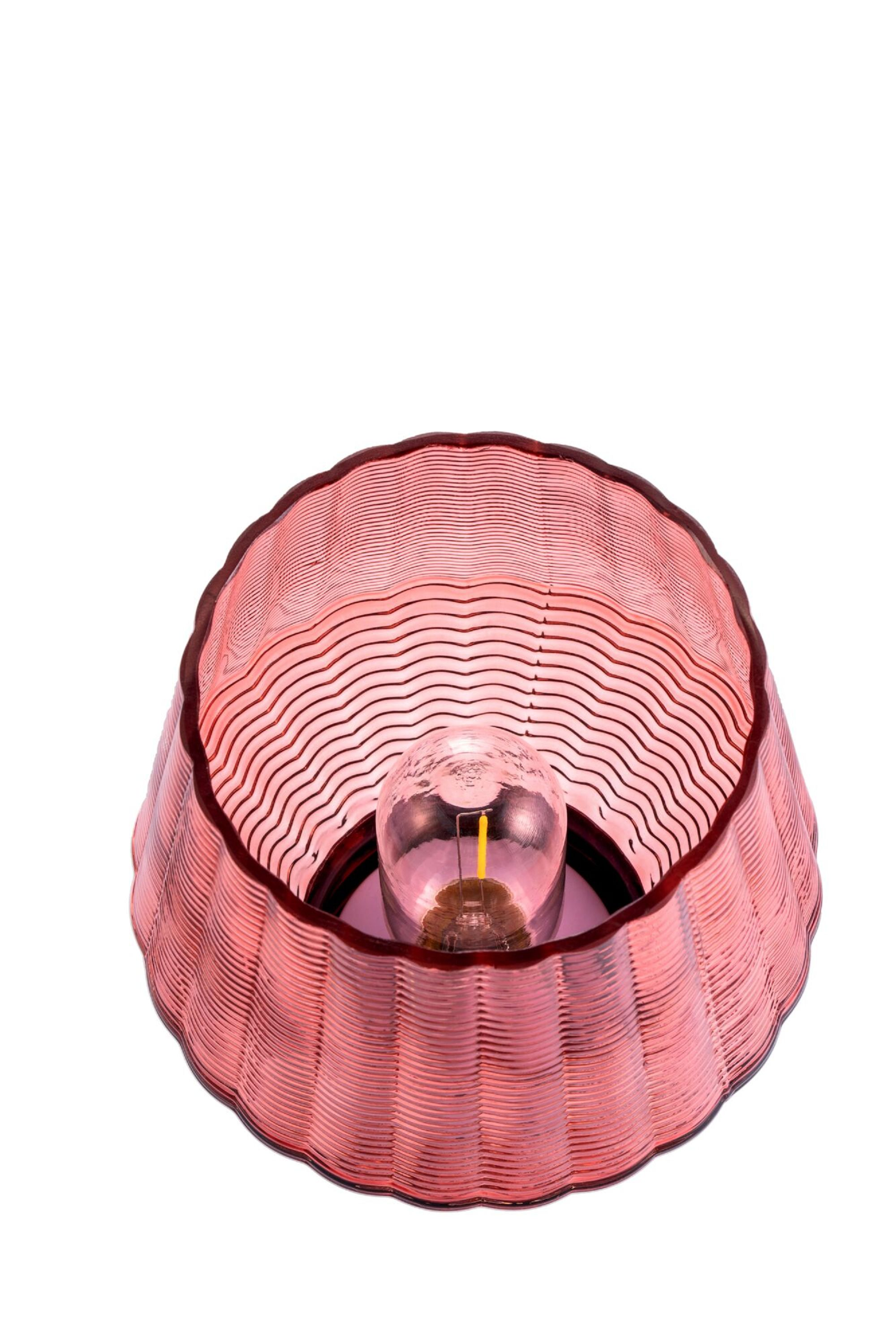 Rote Lampe mit Wellenmuster. Die Lampe hat eine Glühbirne und steht vor weißem Hintergrund.