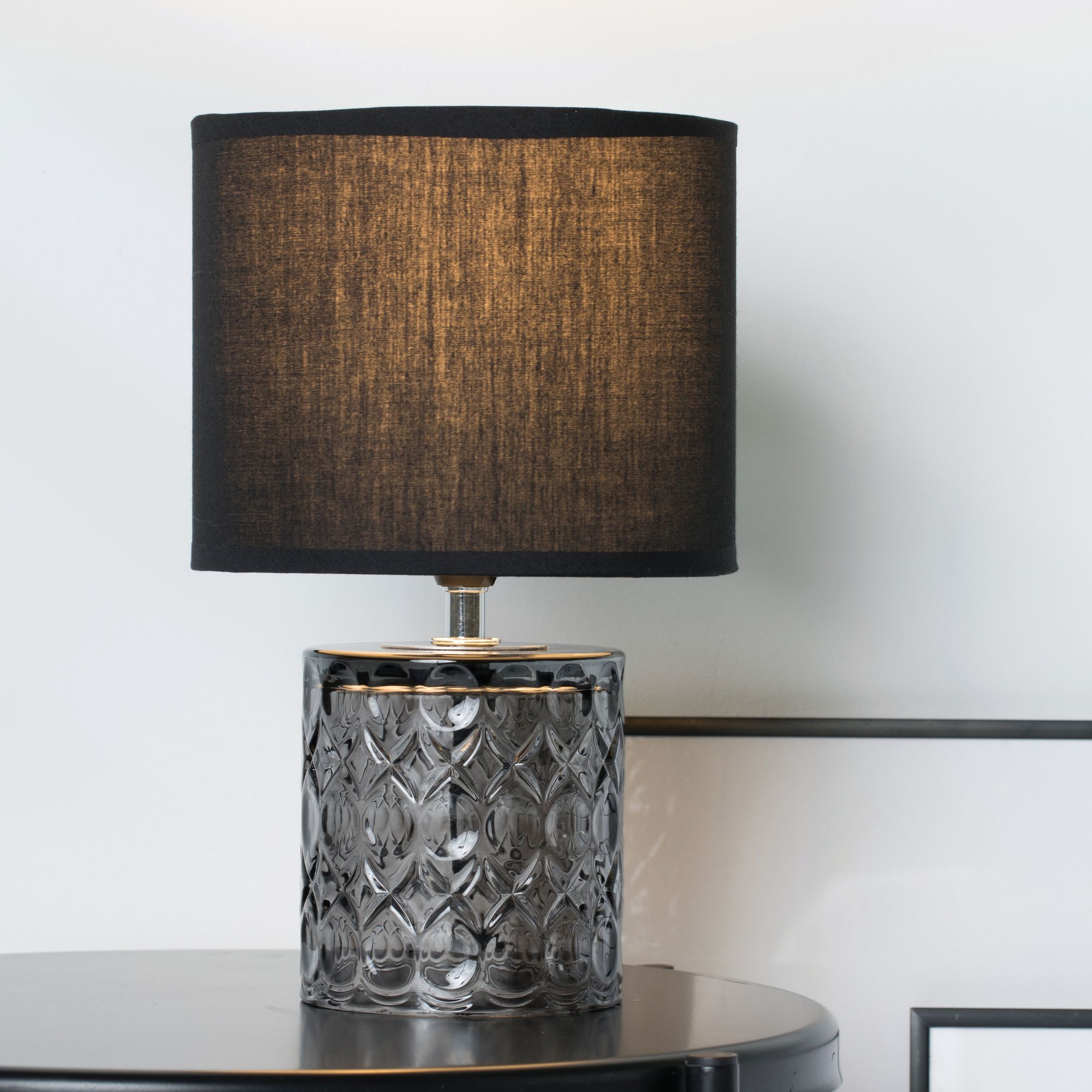 Czarny klosz na czarnej lampie z szarą, teksturowaną podstawą.