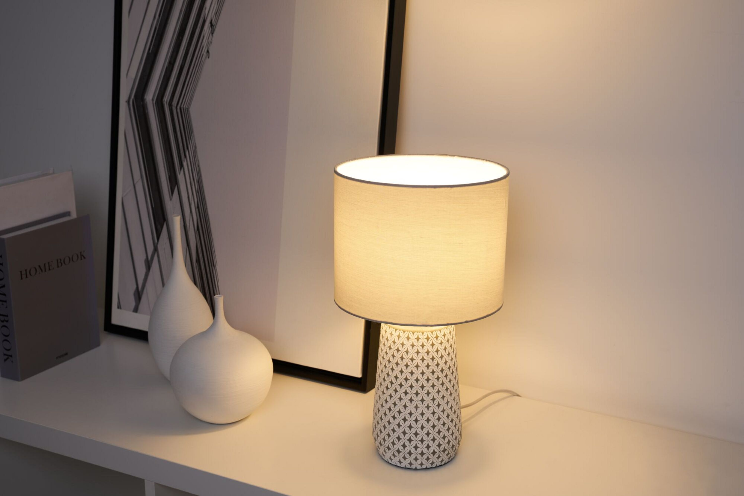 Lampa stołowa z białą podstawą i szarym abażurem.