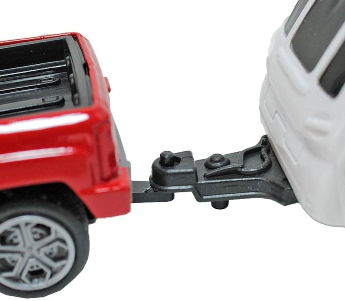 Zwei Spielzeugautos, verbunden durch eine schwarze Anhängerkupplung. Ein roter LKW und ein weißer SUV.