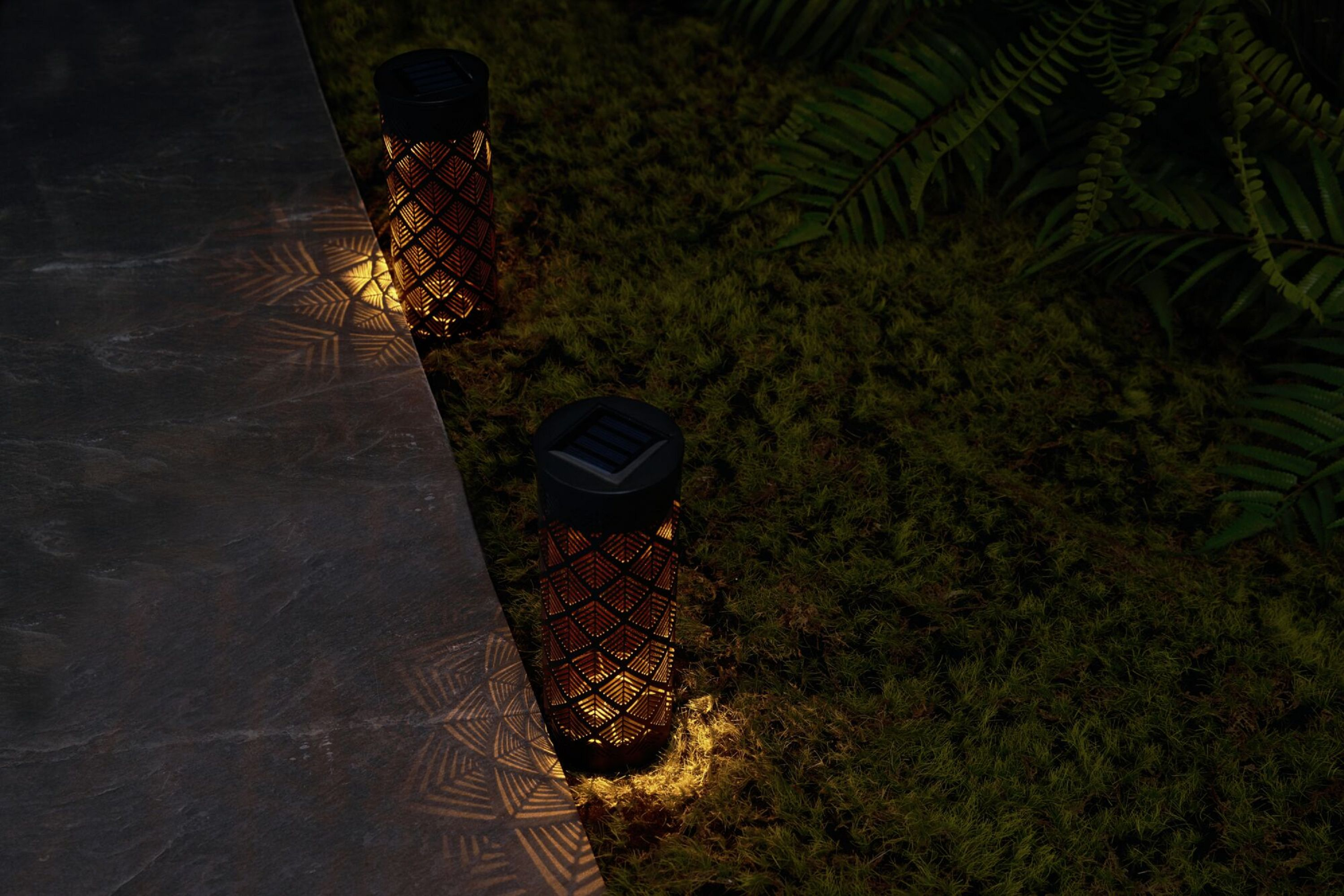Zwei solarbetriebene Lichter auf einem Weg. Die Lichter sind braun mit komplizierten Mustern.