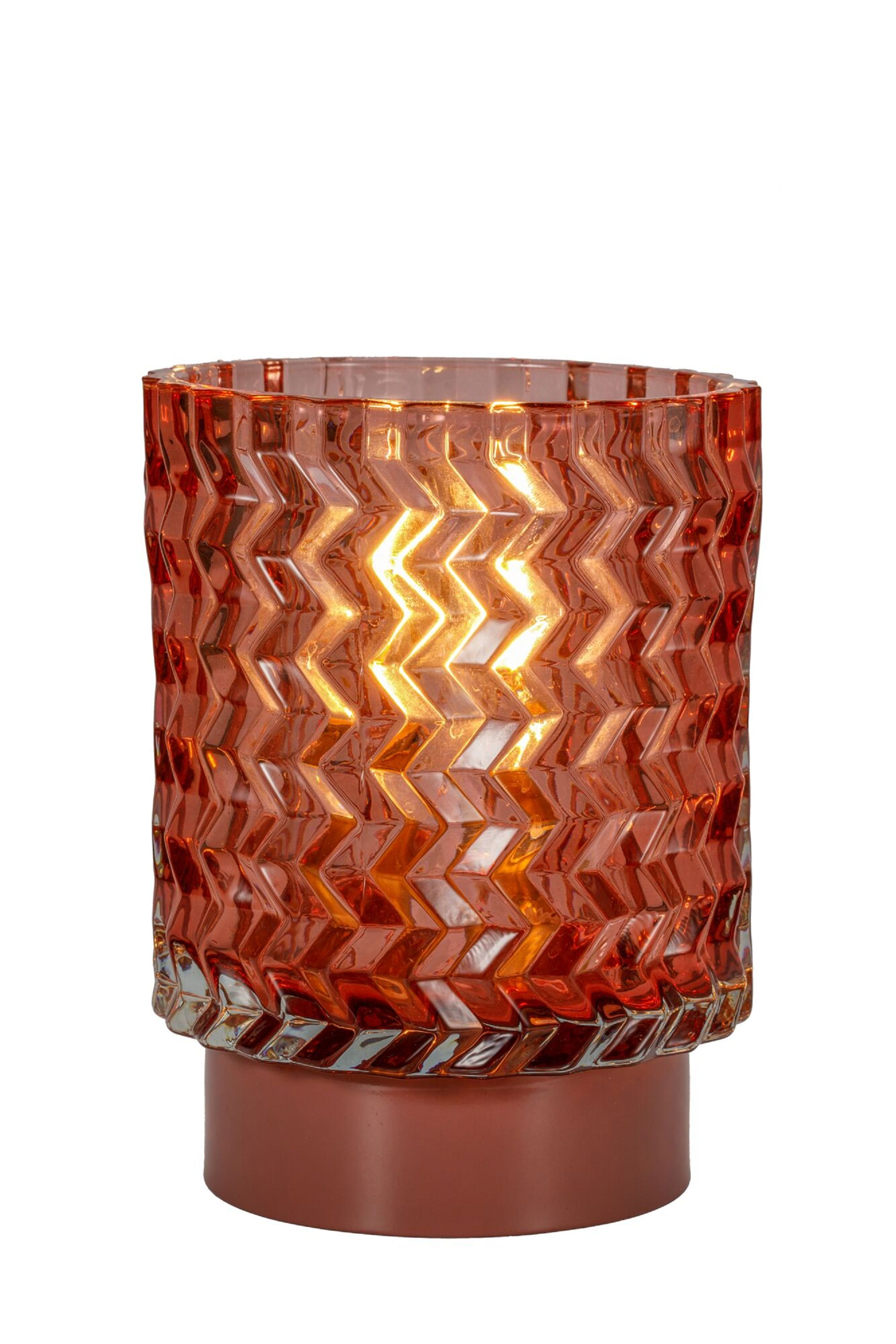 Podświetlana pomarańczowa szklana lampa z zygzakowatym wzorem, na brązowej podstawie, białe tło.