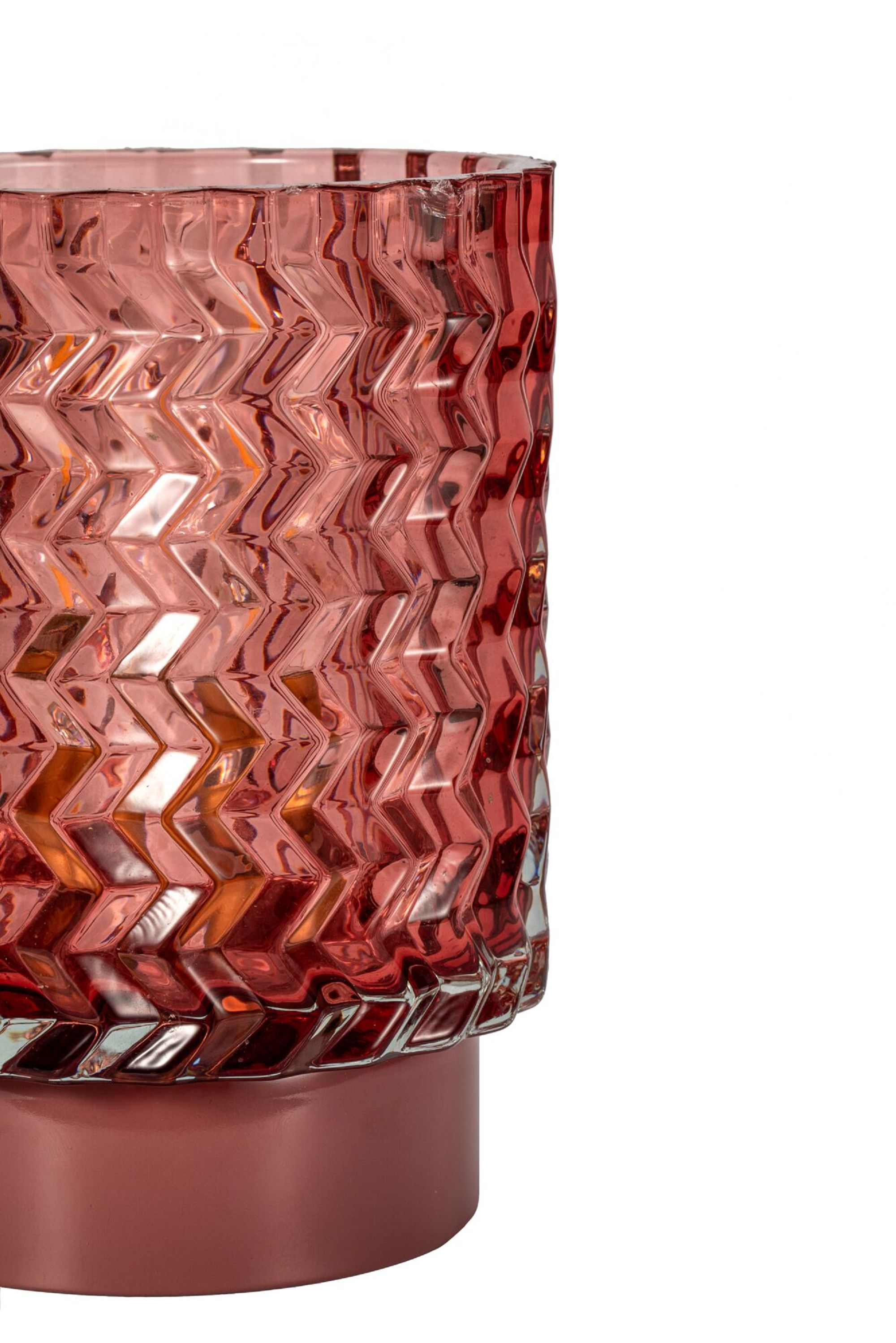 Czerwony szklany wazon ze wzorem zygzaka na czerwonej podstawie. Białe tło.