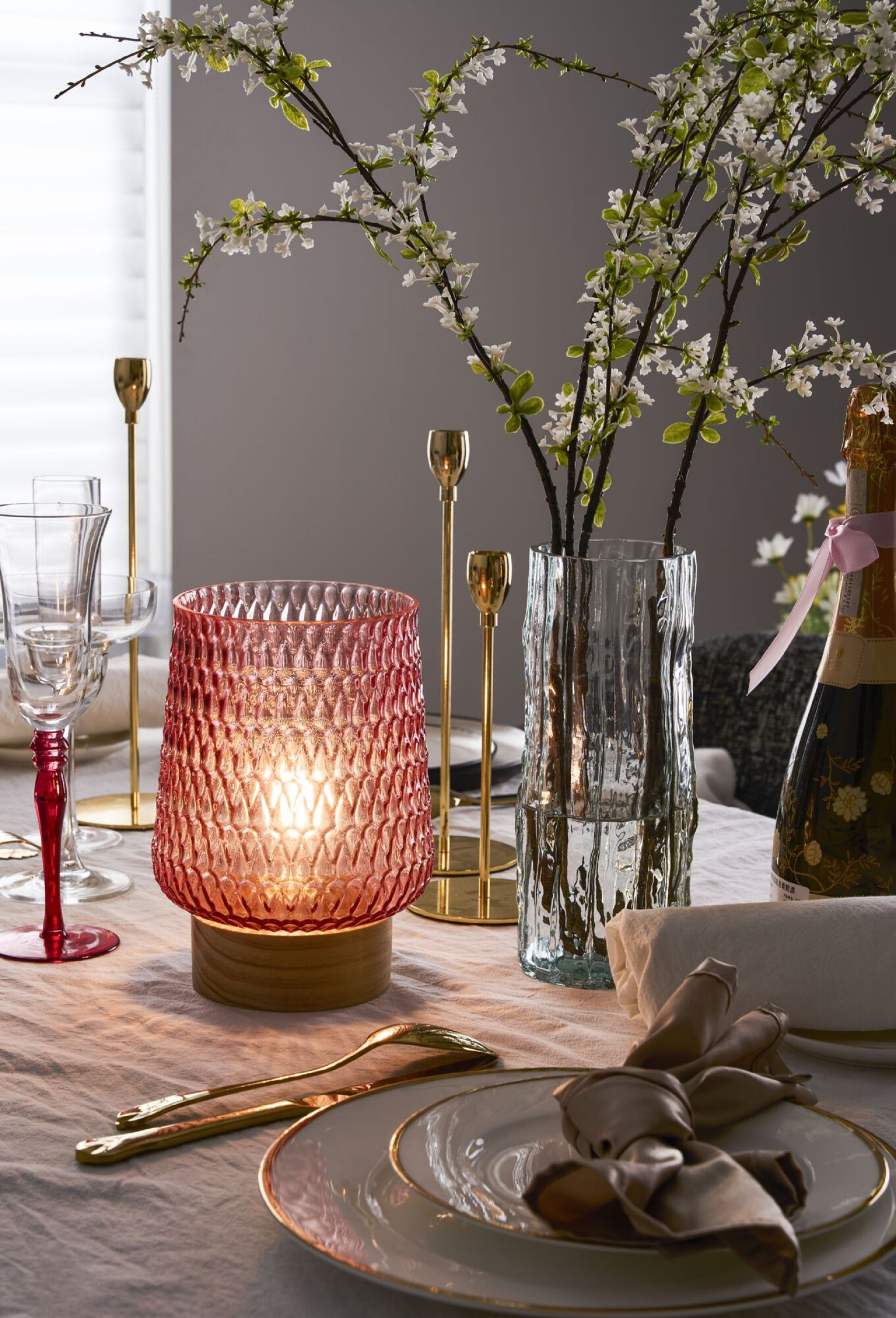 Stół z czerwoną lampą, kwiatami, szampanem i talerzami. 