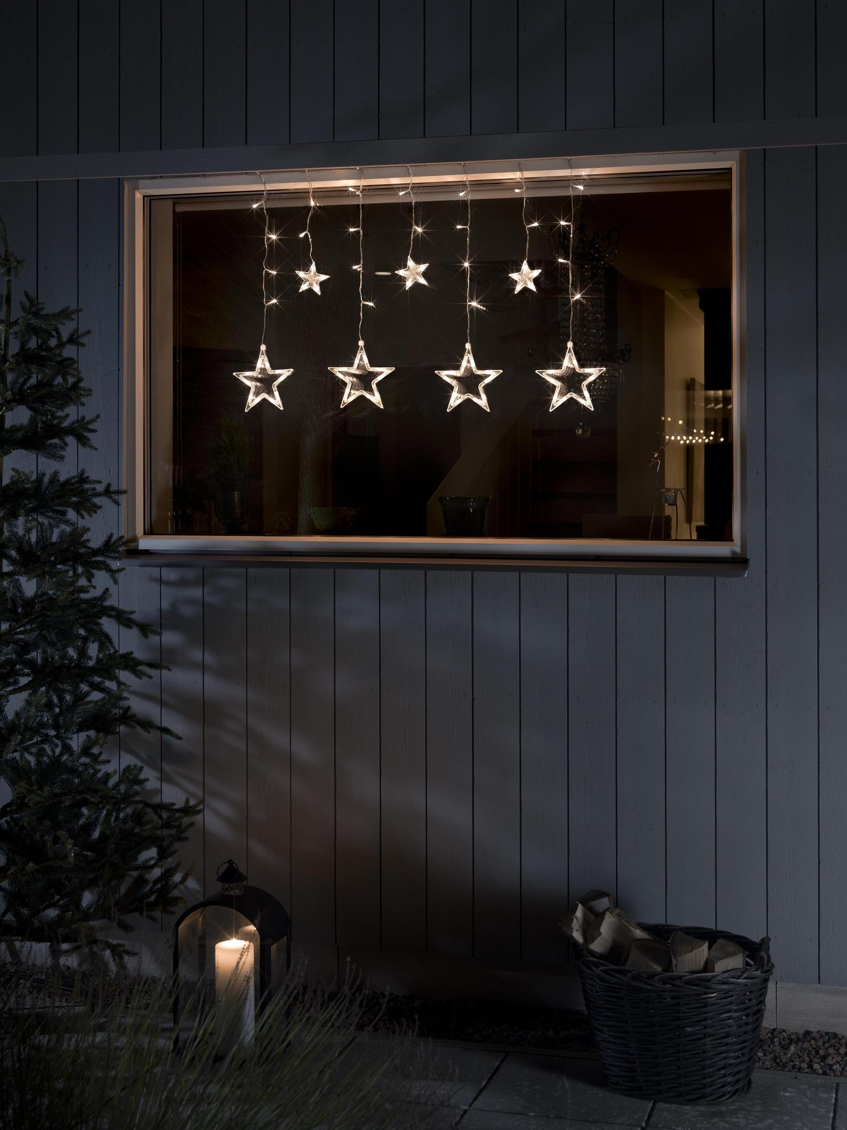 Ein Fenster mit sternförmigen Lichtern davor, sowie eine Kerzenlaterne und ein Korb.