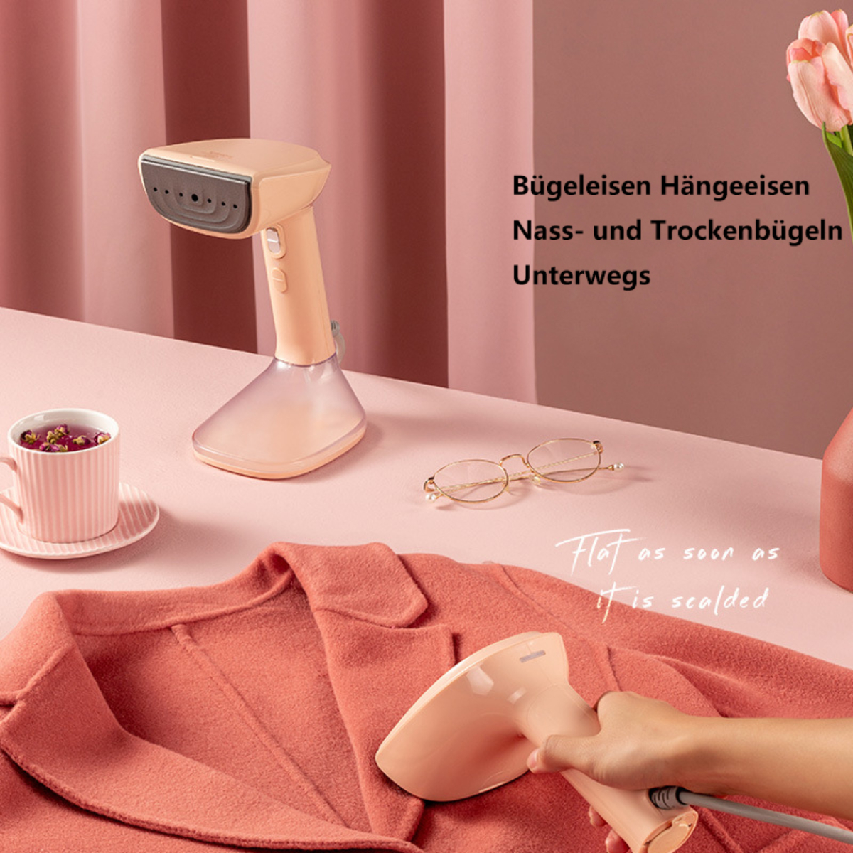 Handdampfbügeleisen, rosa Tasse, Brille und Kleidung auf einer Oberfläche.