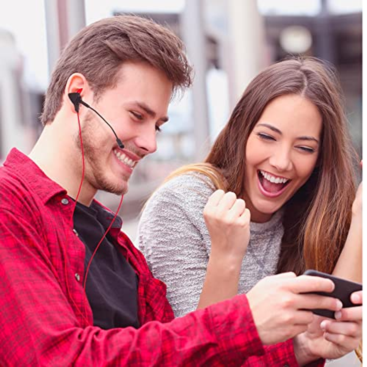 Mężczyzna w zestawie słuchawkowym uśmiecha się, kobieta cieszy się patrząc na telefon. Oboje są szczęśliwi.