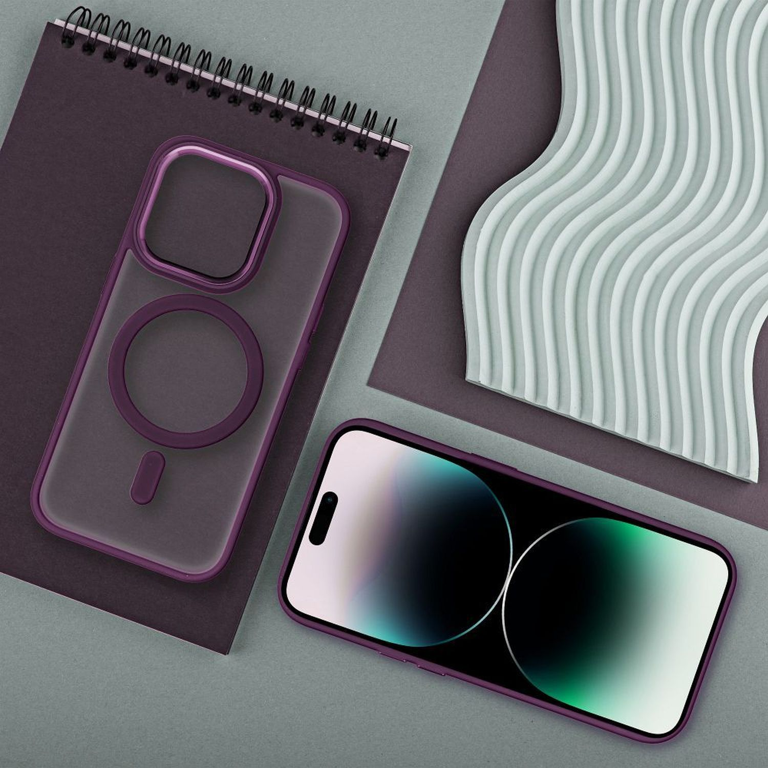 Custodia e telefono su una superficie grigia con un quaderno a spirale e un design ondulato.