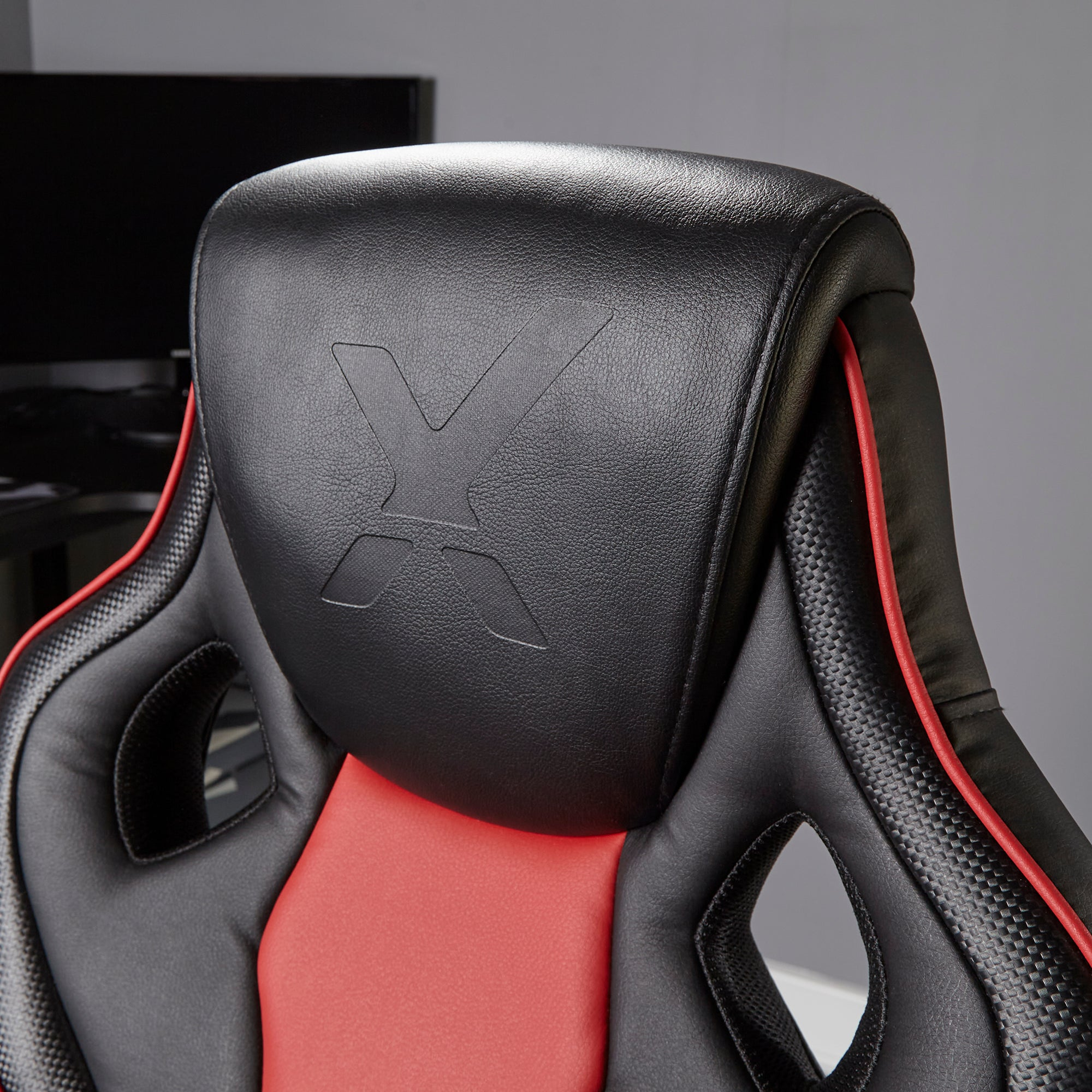 Kopfstütze eines Gaming-Stuhls mit rotem Streifen und schwarzem X-Logo.