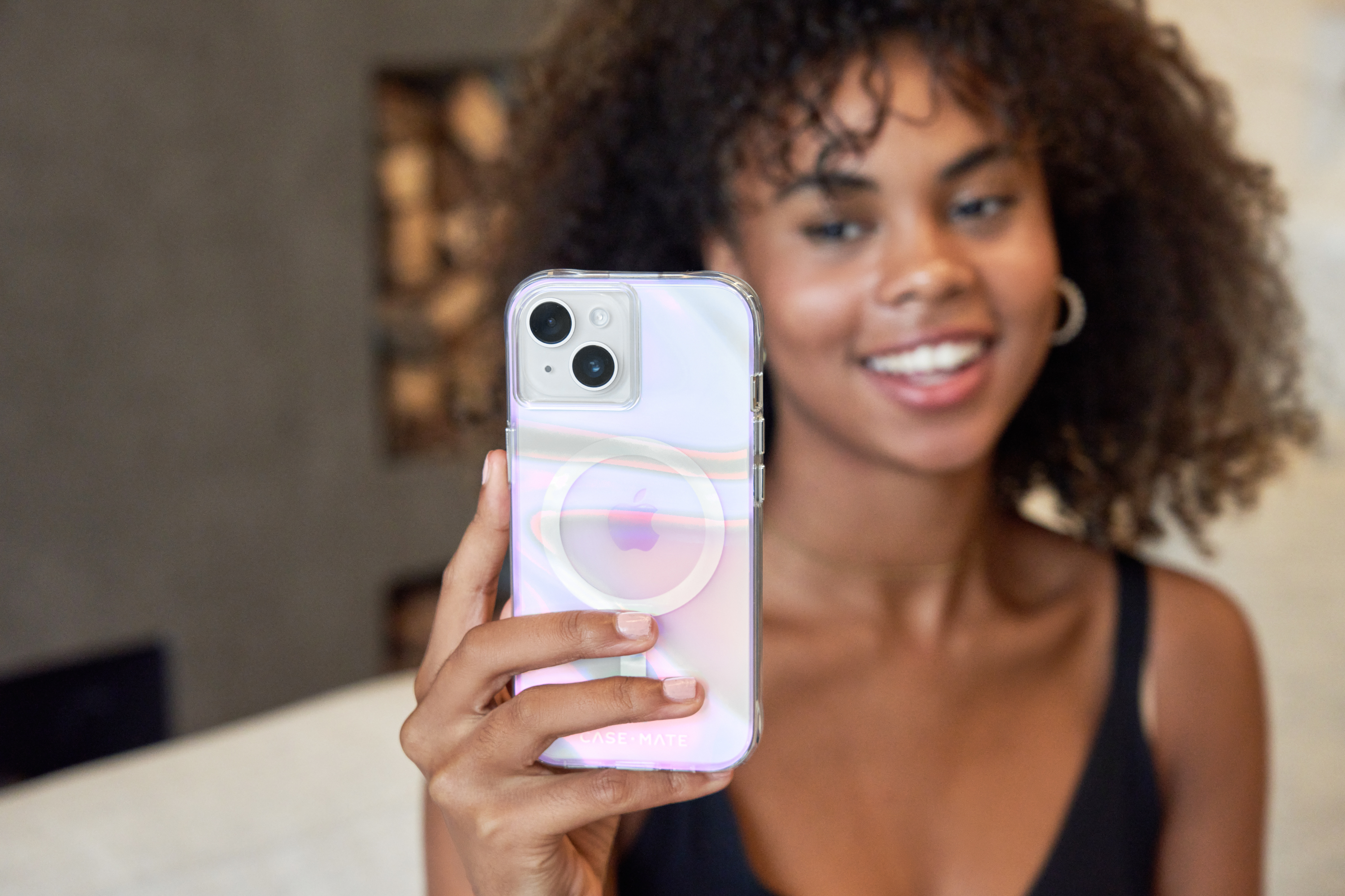 Una donna tiene una custodia per telefono con un iPhone. La custodia ha un retro trasparente e un cerchio bianco.