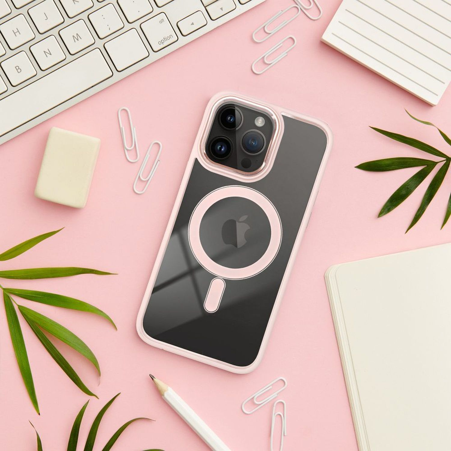 Ein iPhone in einer rosa Hülle mit Apple-Logo, umgeben von Schreibtischutensilien auf rosa Oberfläche.