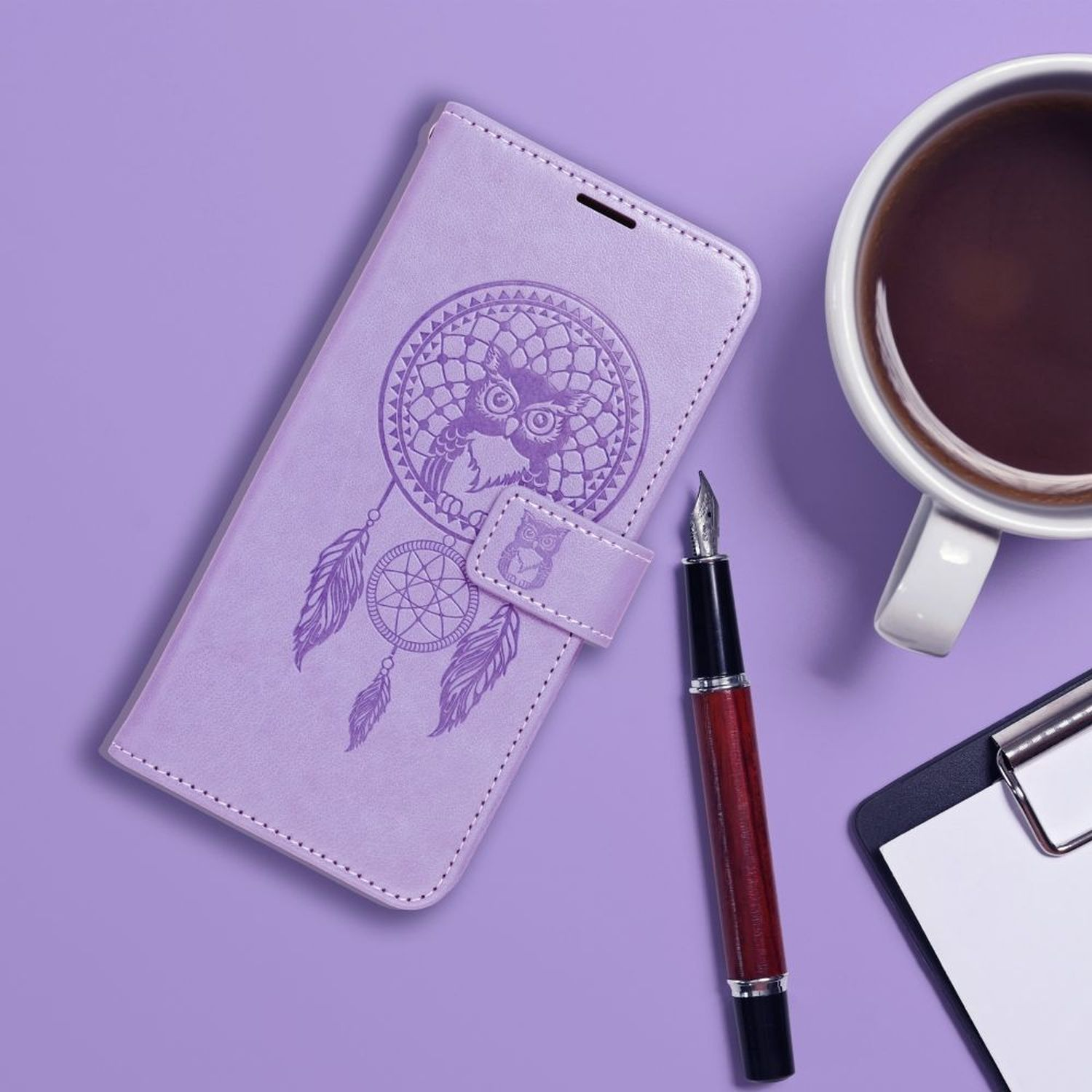 Eine lila Handyhülle mit Traumfänger-Design, einem Stift und einer Tasse Kaffee.