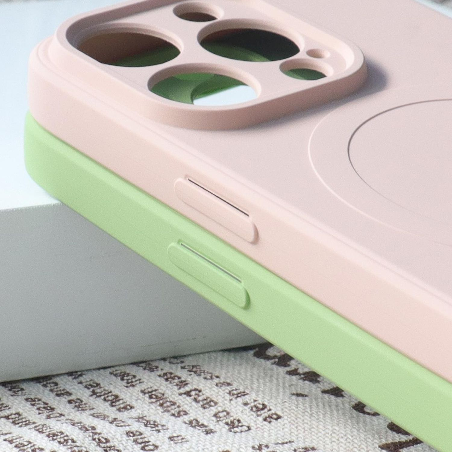 Zwei Handyhüllen, eine rosa oben auf einer grünen. Beide haben ein Design für die Kamera eines Telefons.