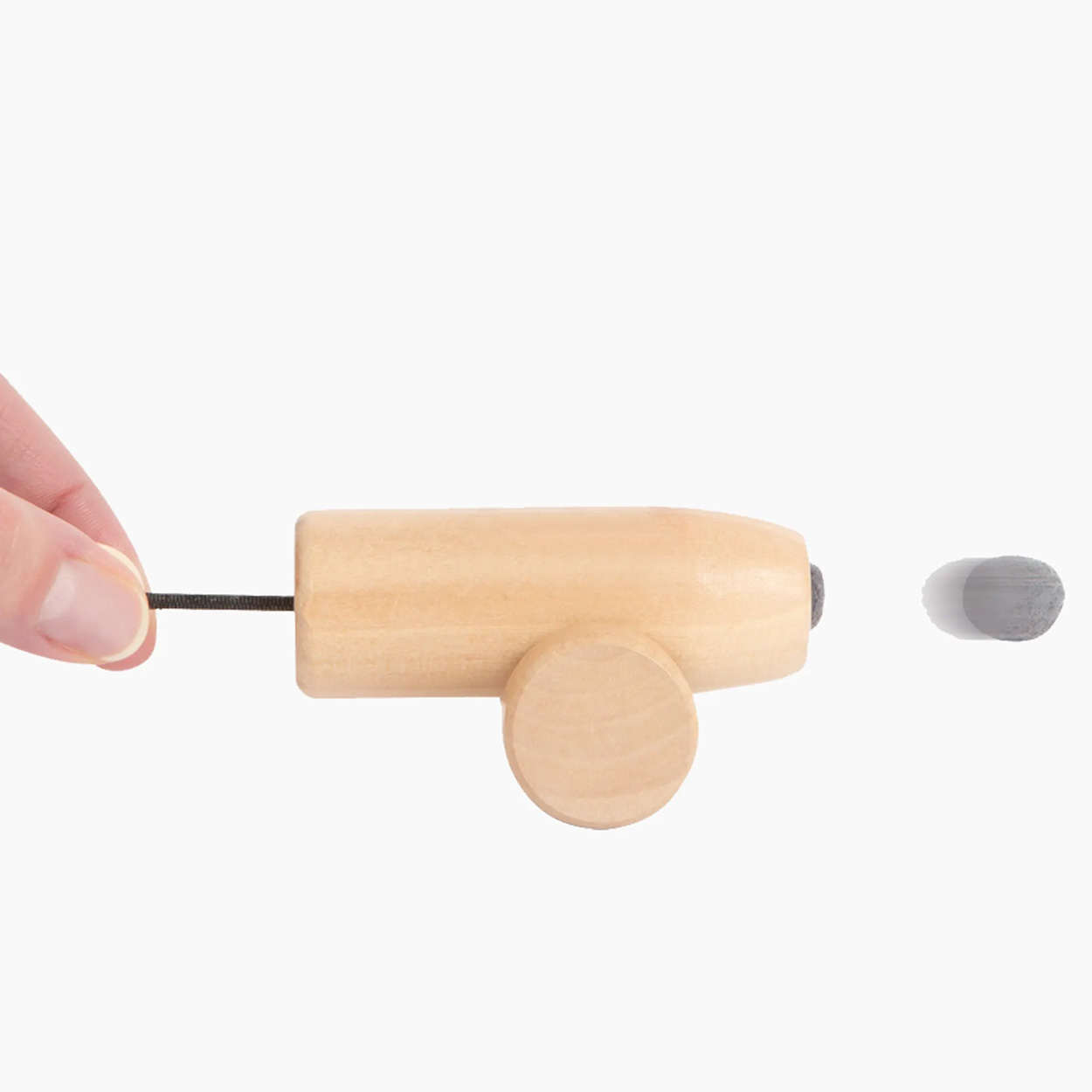 Un petit canon en bois avec une ficelle tirée par une main. Un projectile gris en mouvement.