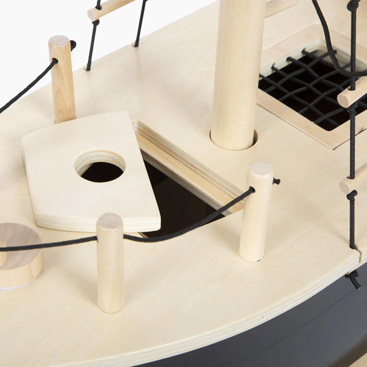 Bateau jouet en bois avec mâts et détails. Coque noire, pont clair, cordes noires.