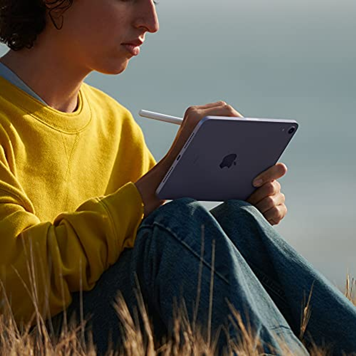 Eine Person benutzt ein violettes Tablet und hält einen weißen Stift.