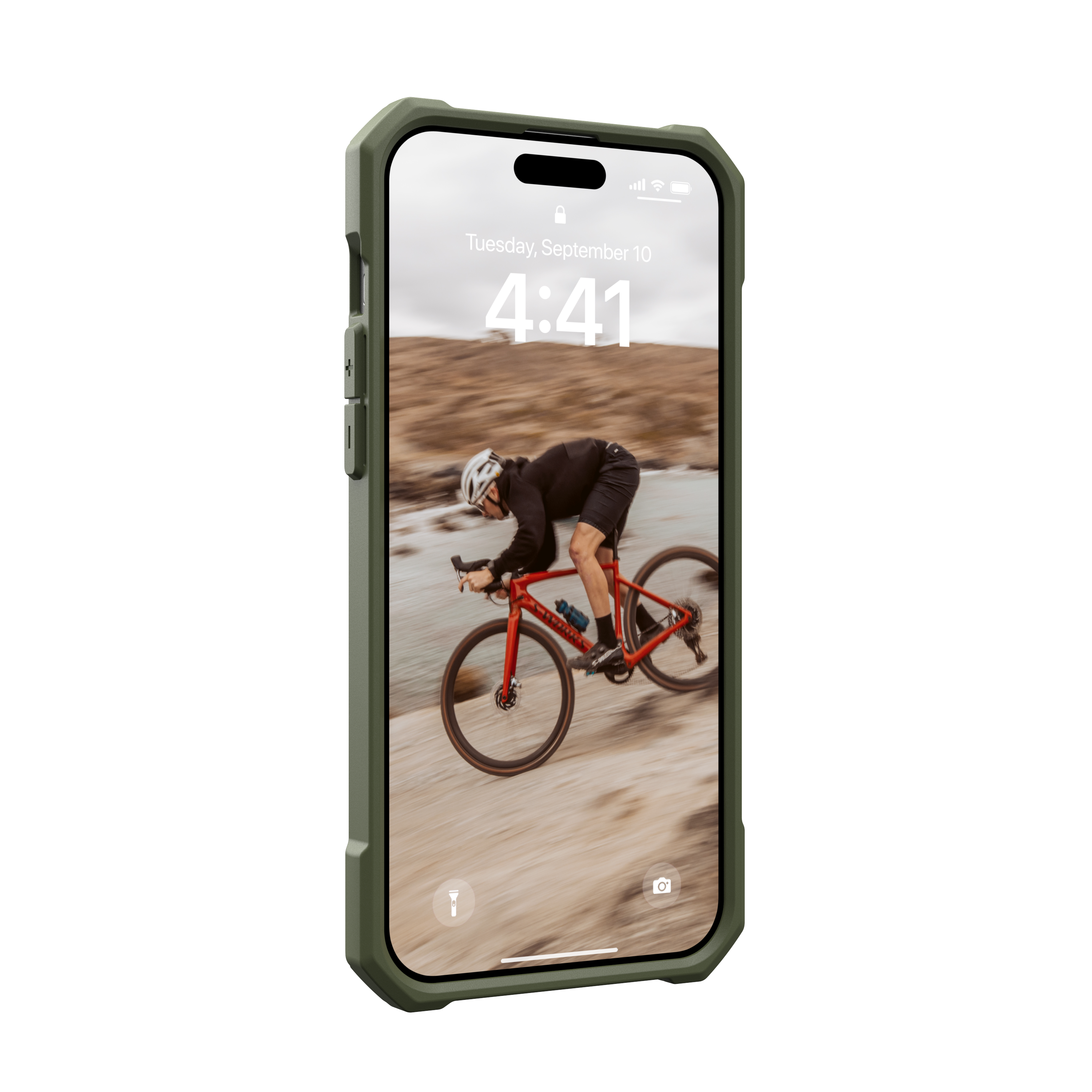 Phone in a green case showing a cyclist on a beach. The screen displays the time and a date.