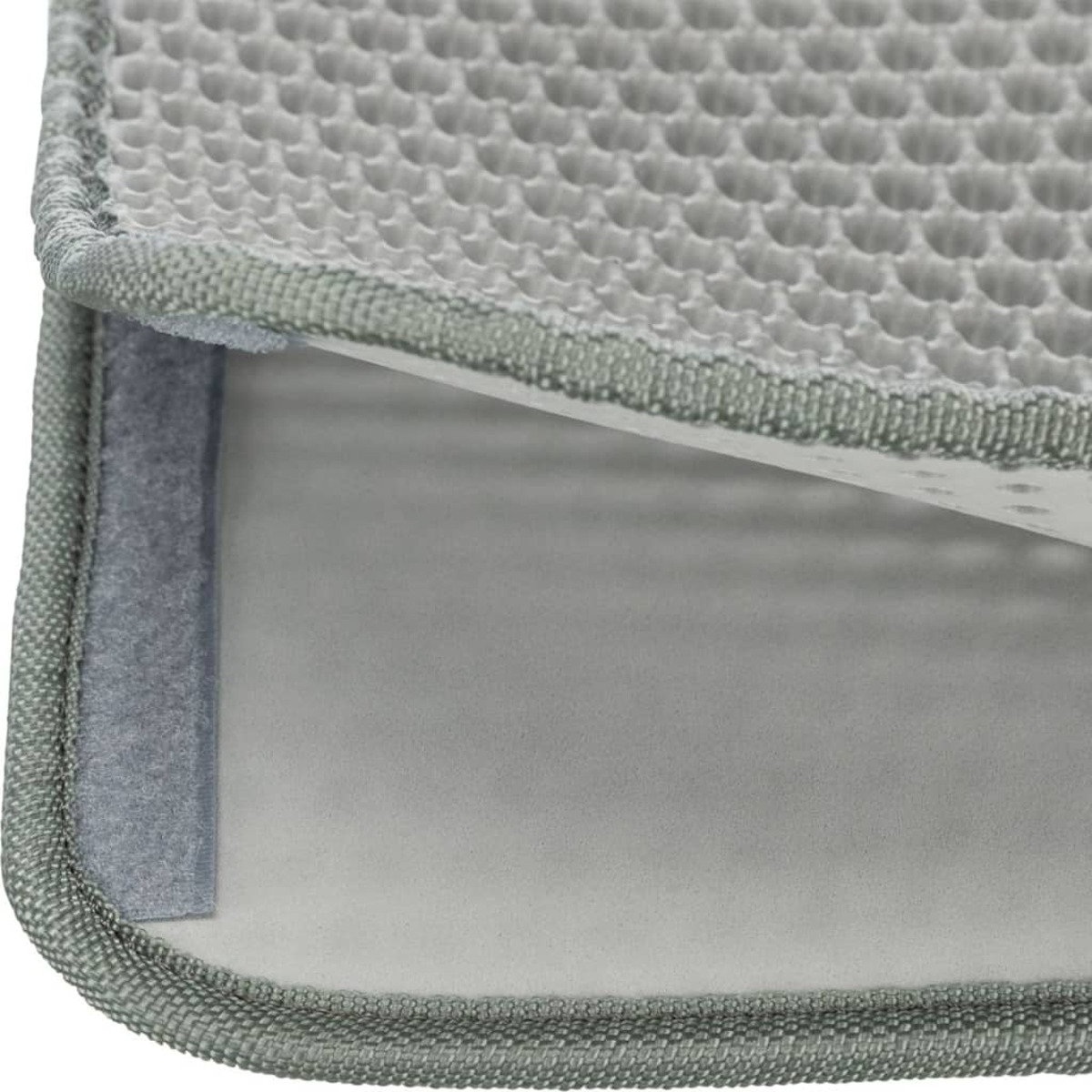 Primer plano de una alfombrilla gris para arena de gato. La alfombrilla tiene un patrón de panal y bordes grises.