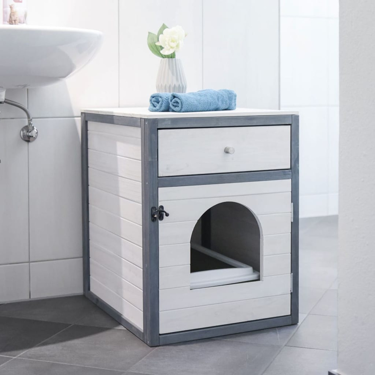 Un mobile bianco con cassetto e porta per gatti. Ambiente bagno.