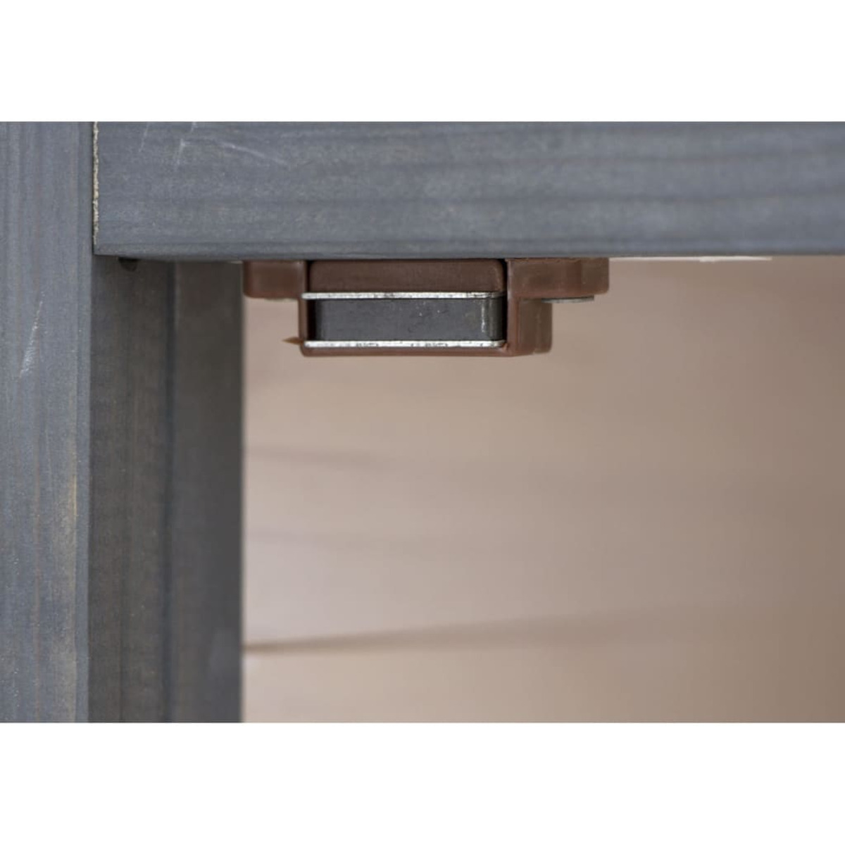 Primo piano di un fermo magnetico su mobili in legno. Il fermo è marrone e il legno grigio.