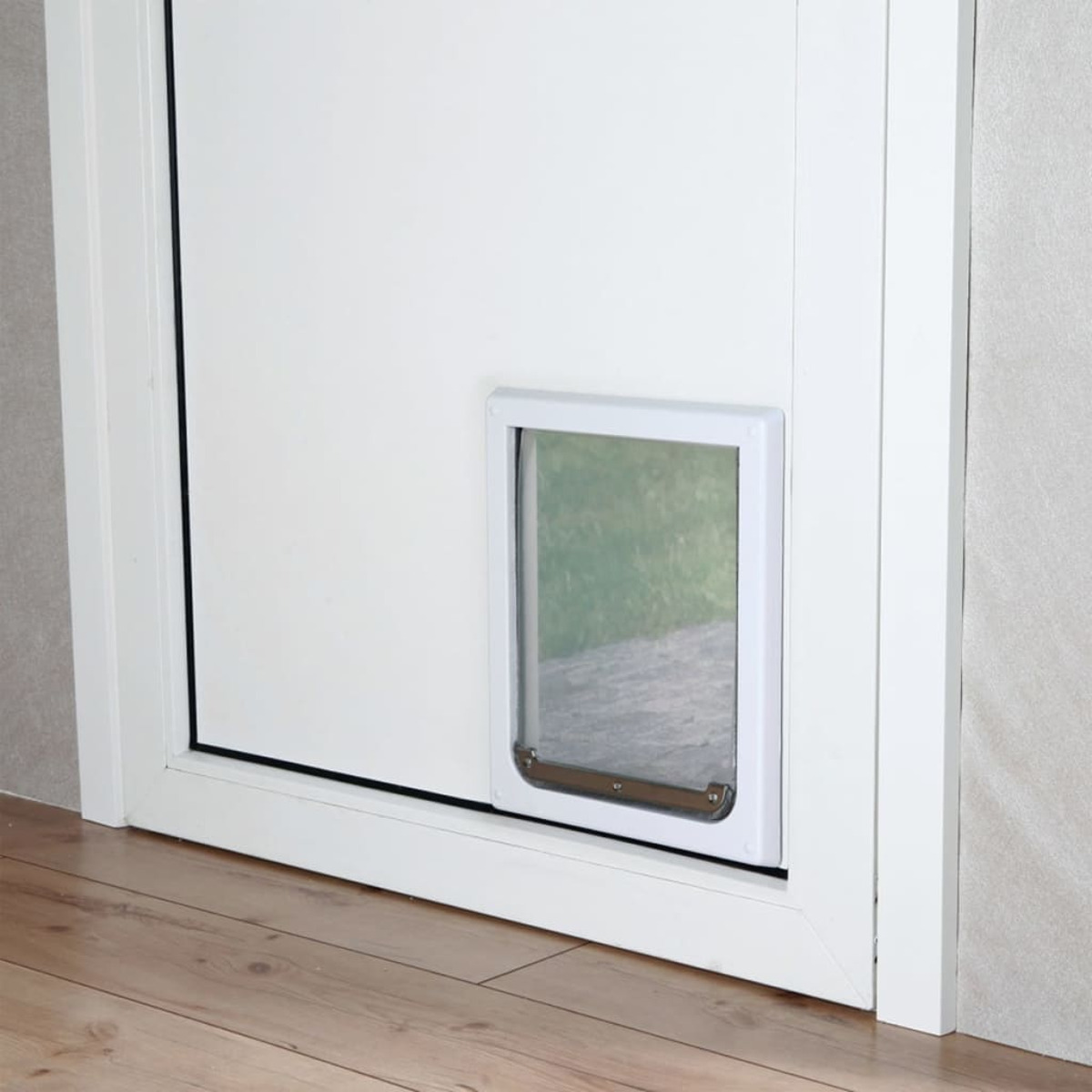 Una puerta blanca con una puerta para mascotas instalada. La puerta está abierta, mostrando el exterior.