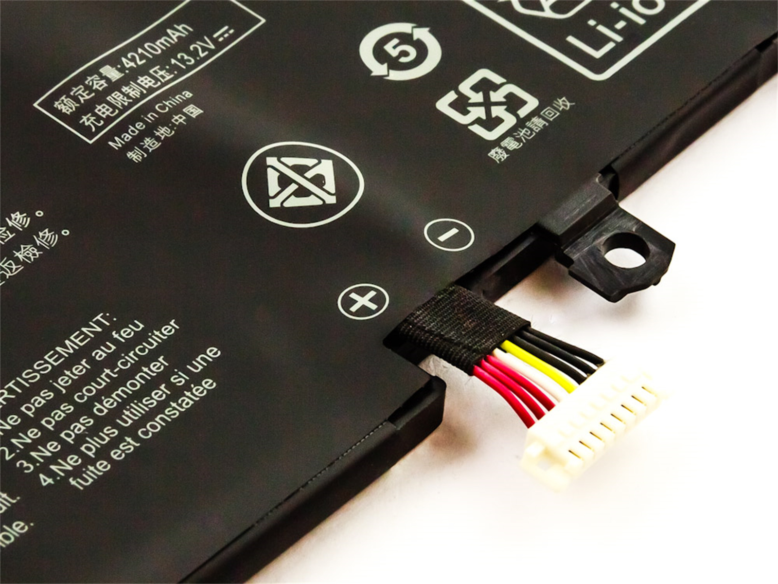 Laptop-Akku mit Warnhinweisen und Anschlusskabel. Schwarz und Weiß mit roten, gelben und weißen Drähten.