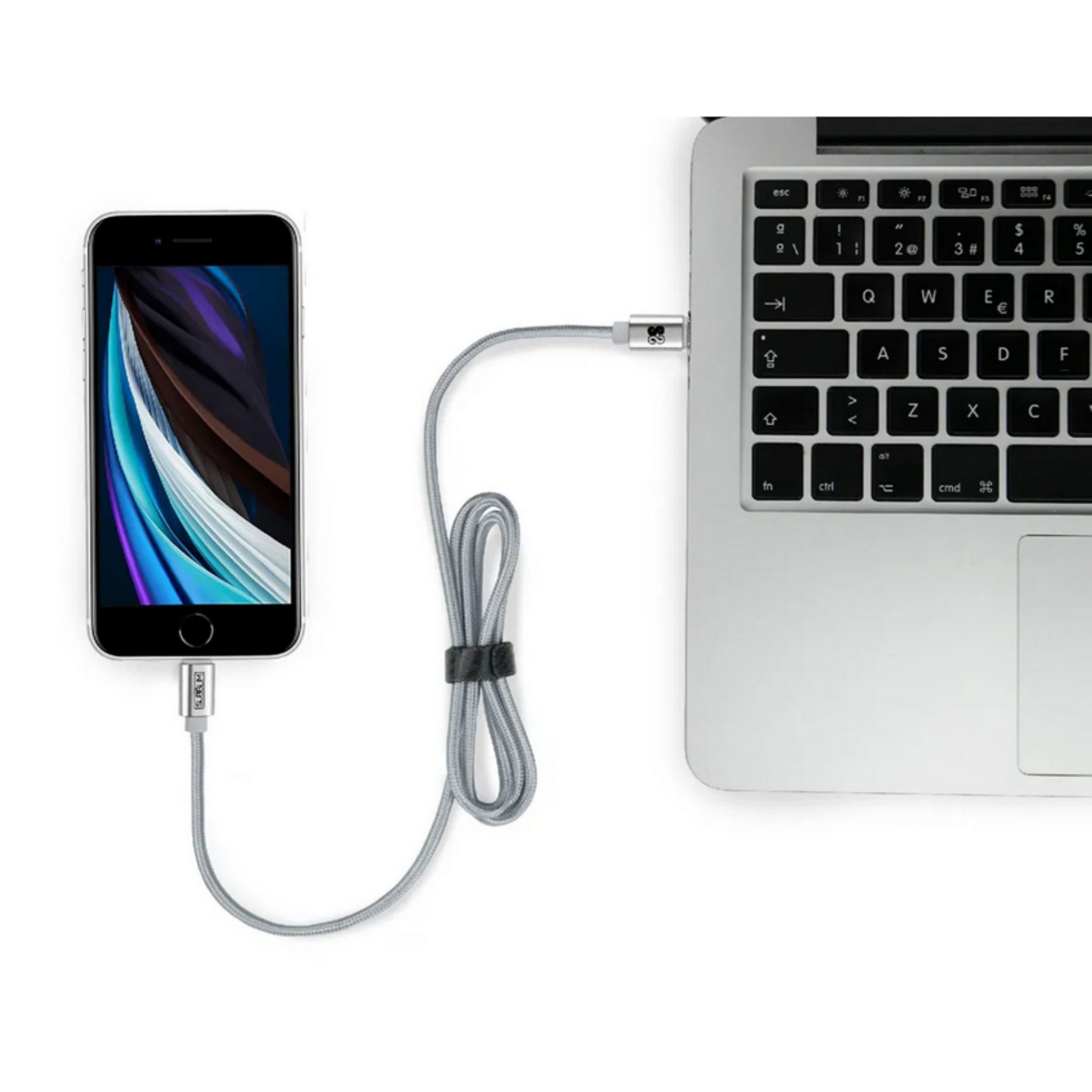 Cable de carga plateado conectando un teléfono a un portátil sobre fondo blanco.