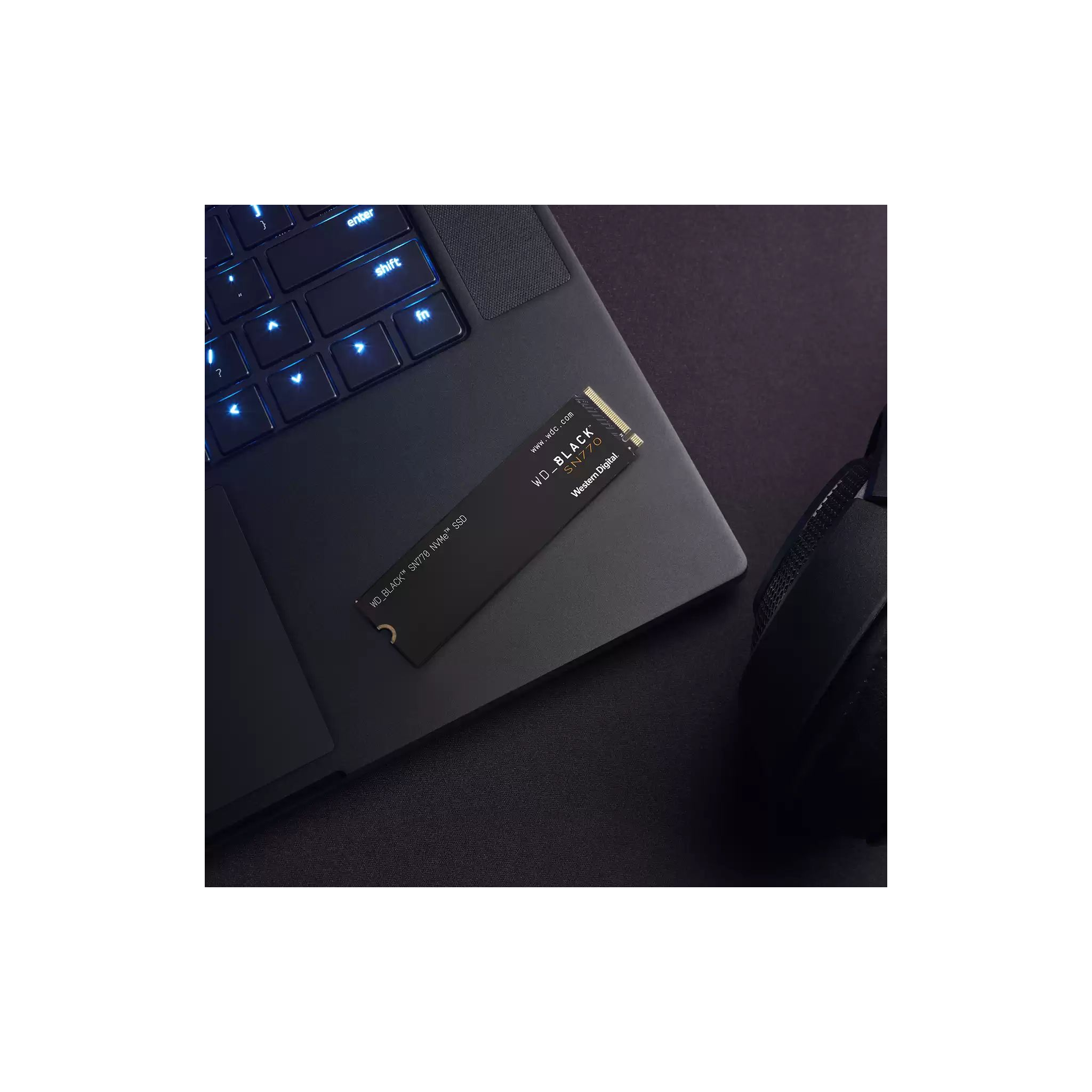 Czarny dysk SSD na laptopie. Czarny dysk SSD na czarnym laptopie, ze słuchawkami.