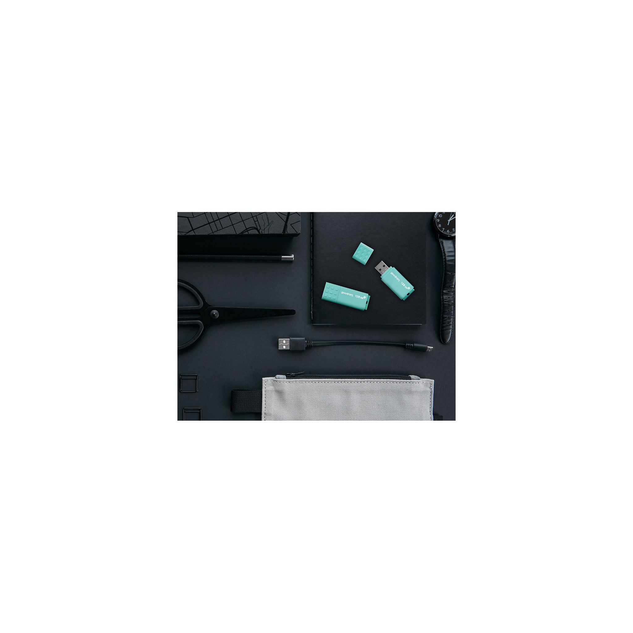 Układ płaski z czarnymi akcesoriami i dwoma turkusowymi dyskami USB na czarnej powierzchni.