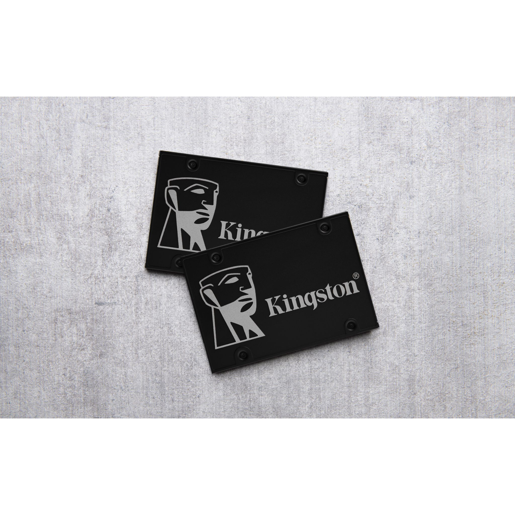 Dwa czarne dyski SSD Kingston na teksturowanej szarej powierzchni. Każdy ma białe logo i nazwę Kingston.