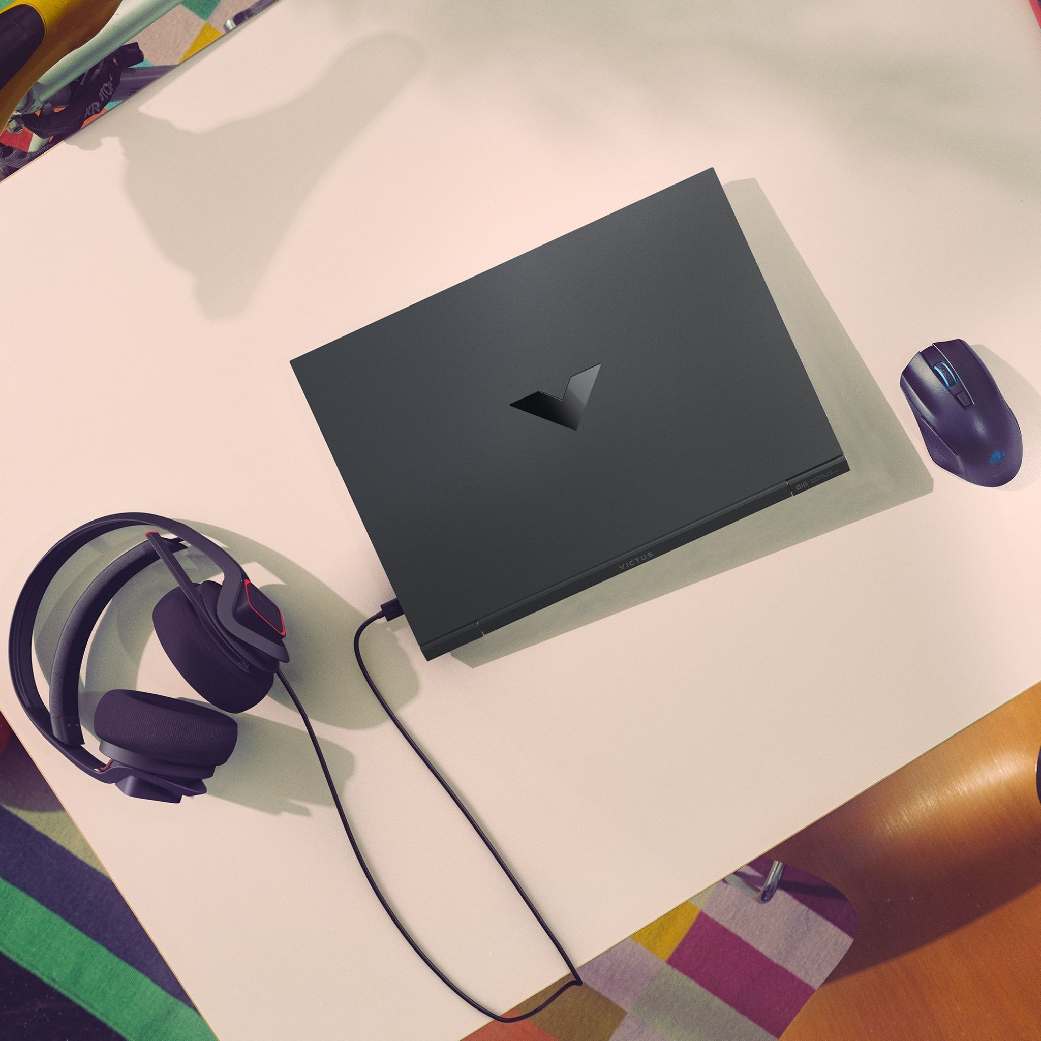 Laptop, auriculares, ratón en un escritorio con papelería. Tema oscuro.