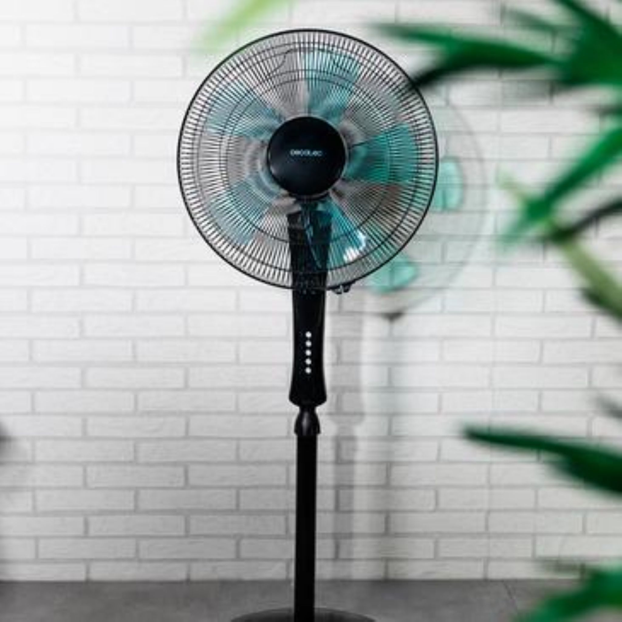 Czarny wentylator z białym tłem z cegieł. Łopatki są szare i turkusowe.