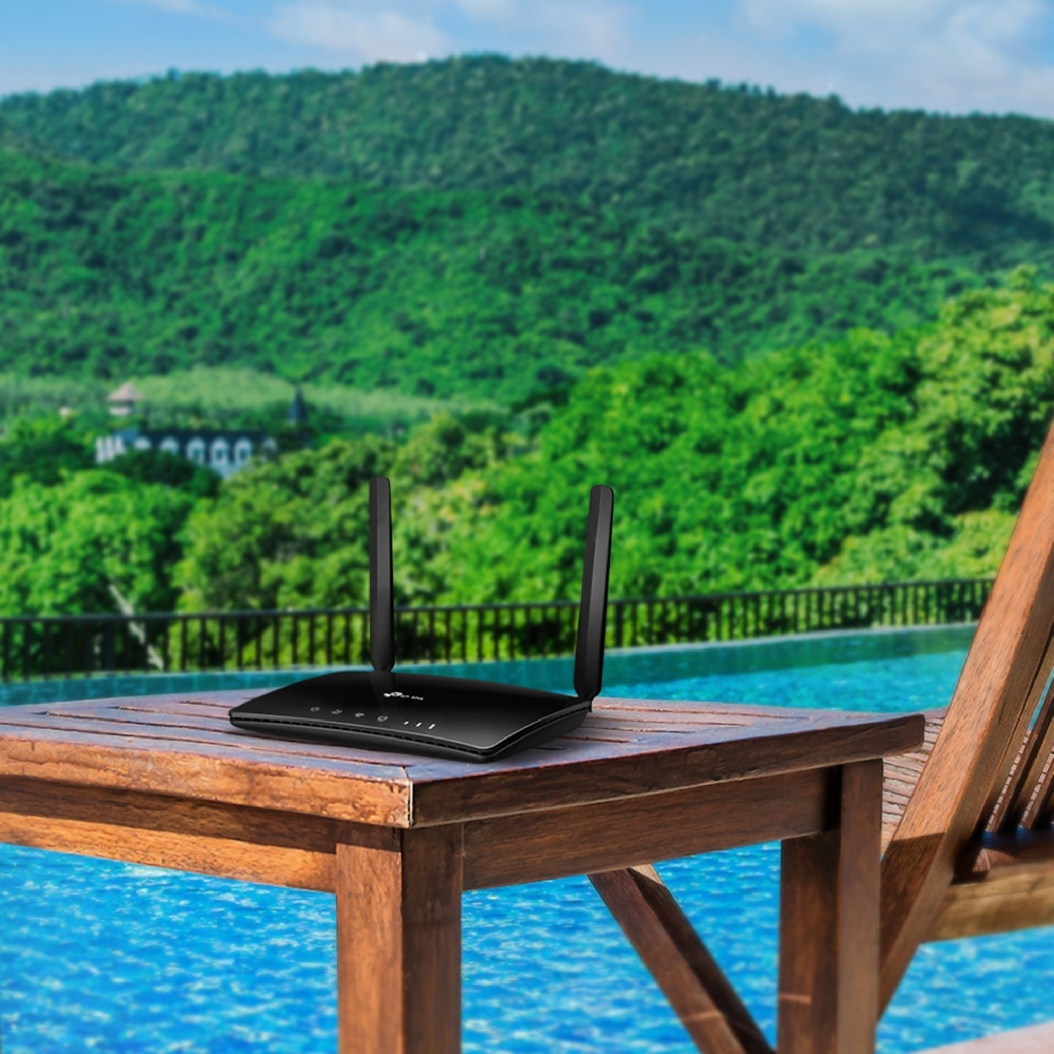 Router na stole przy basenie z górami w tle.