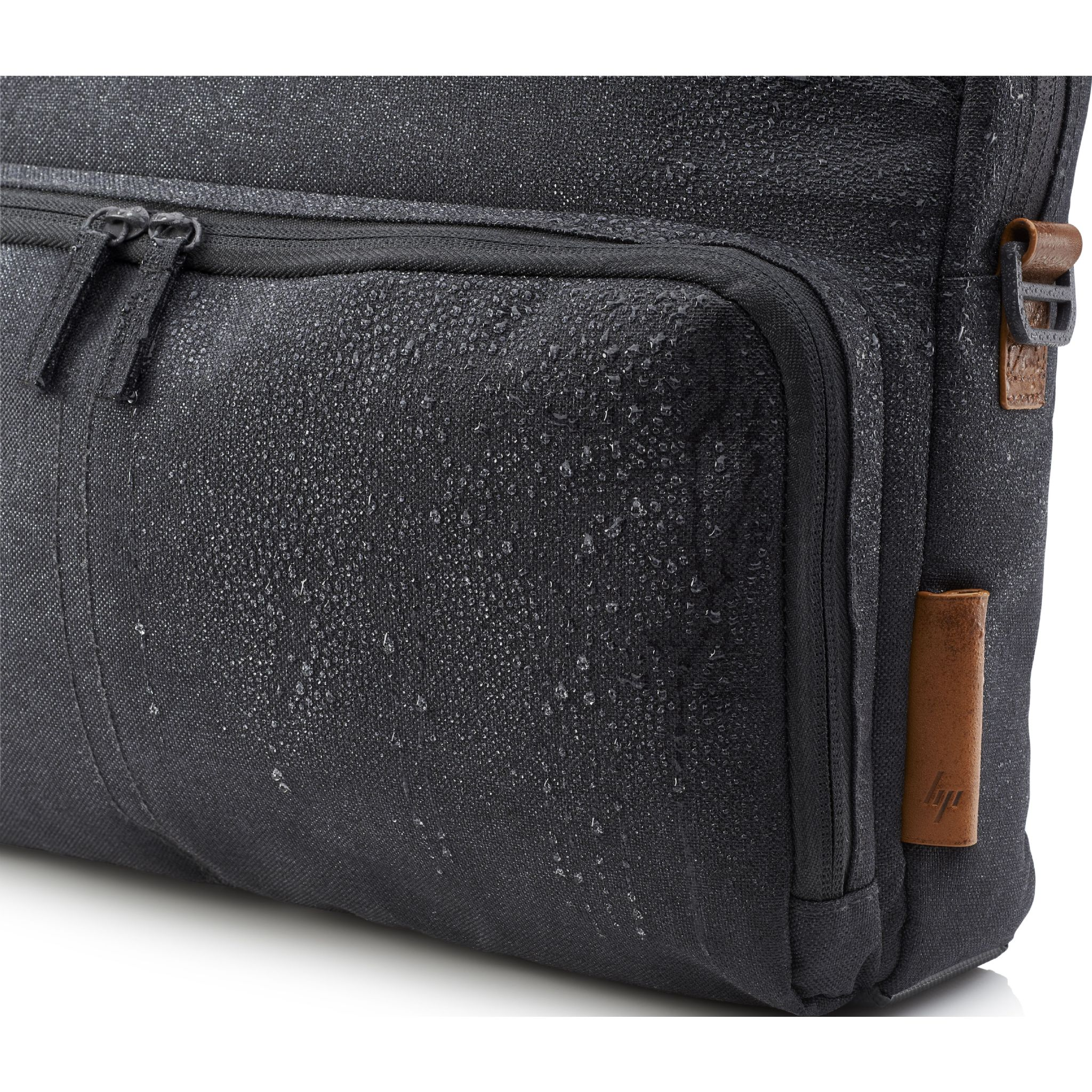 Primo piano di una borsa nera con cerniera, tasca ed etichetta in pelle marrone.
