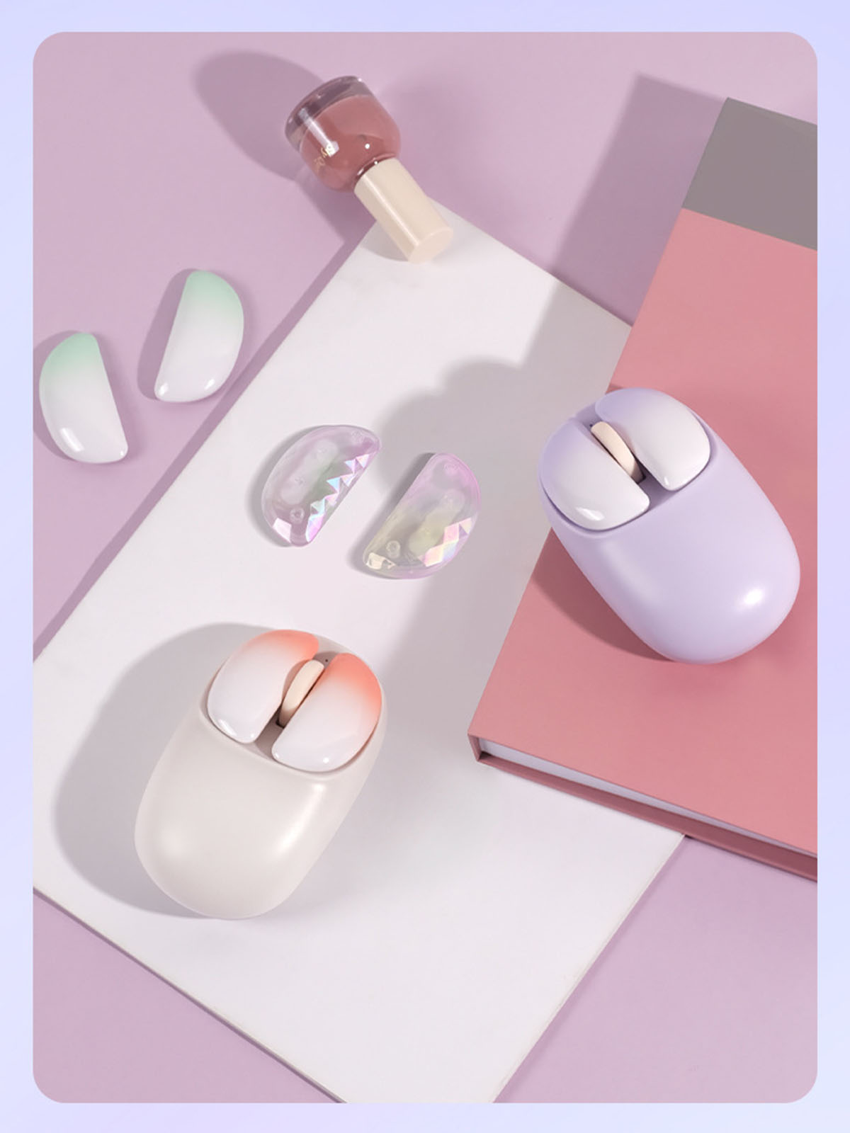 Zwei kleine Computermäuse, Nagellack und dekorative Elemente auf einer rosa-weißen Oberfläche.