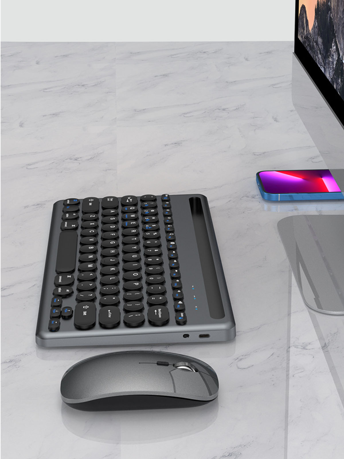Eine Tastatur und Maus auf einem Schreibtisch mit Monitor und Telefon. Die Tastatur ist grau.