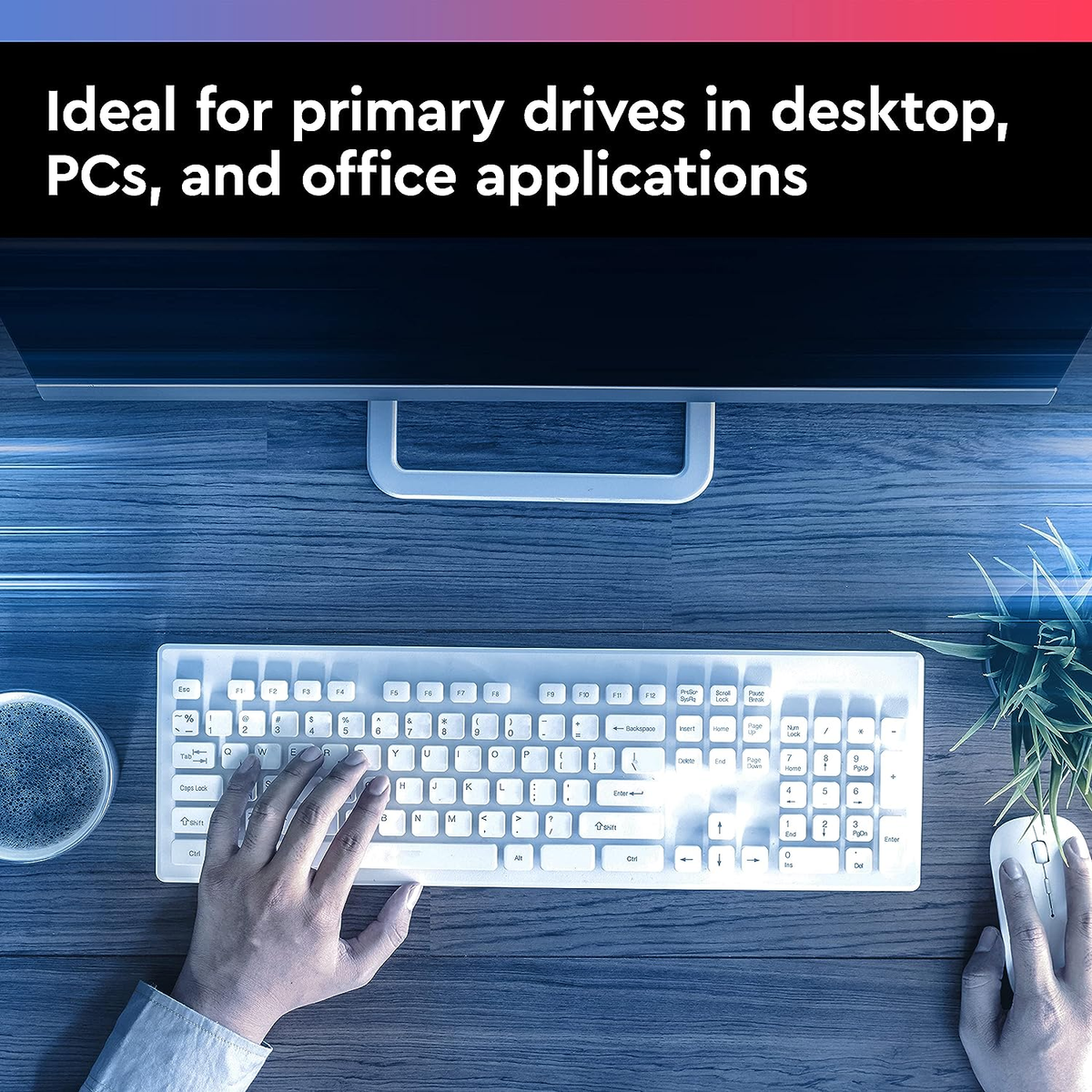 Biurko z klawiaturą, myszką i monitorem. Ręka pisze.