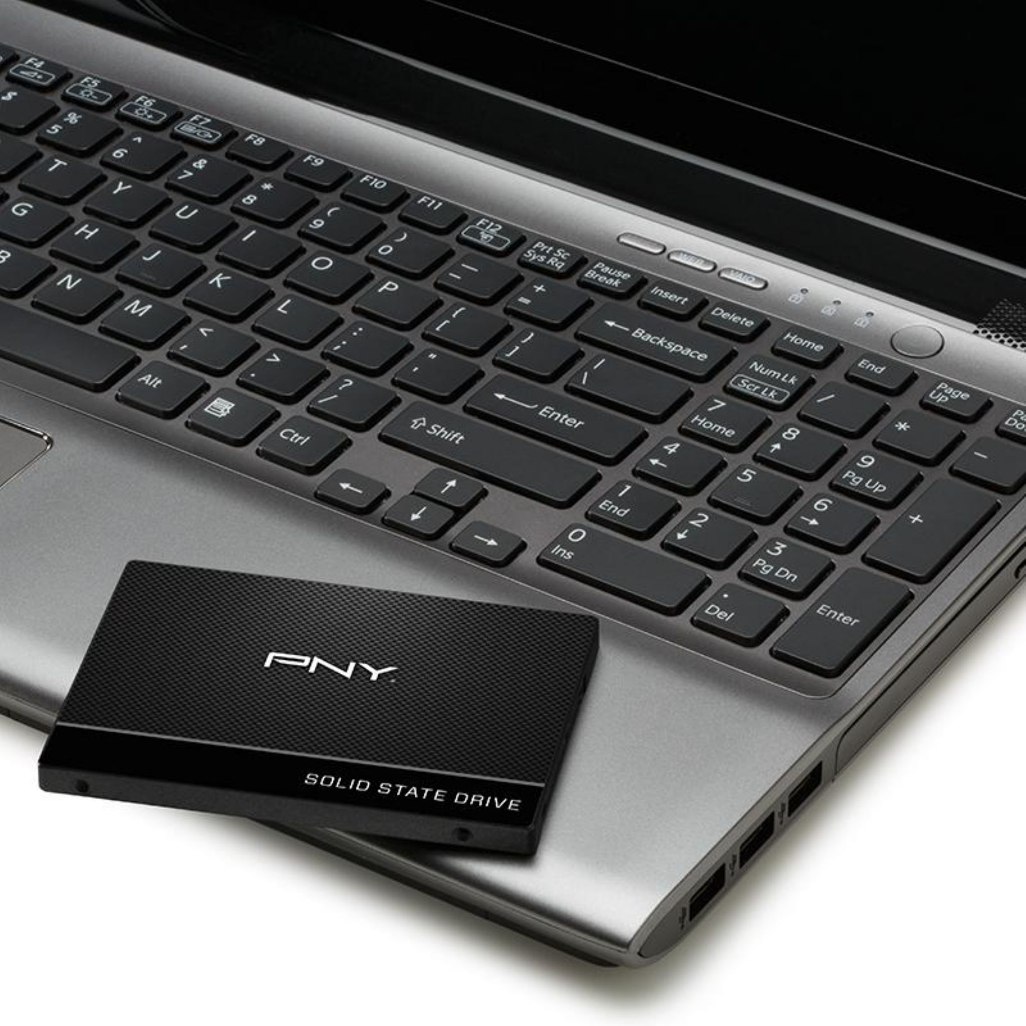 Laptop-Computer und eine schwarze Solid-State-Festplatte. Tastatur und Bildschirm sichtbar. Weißer Hintergrund.